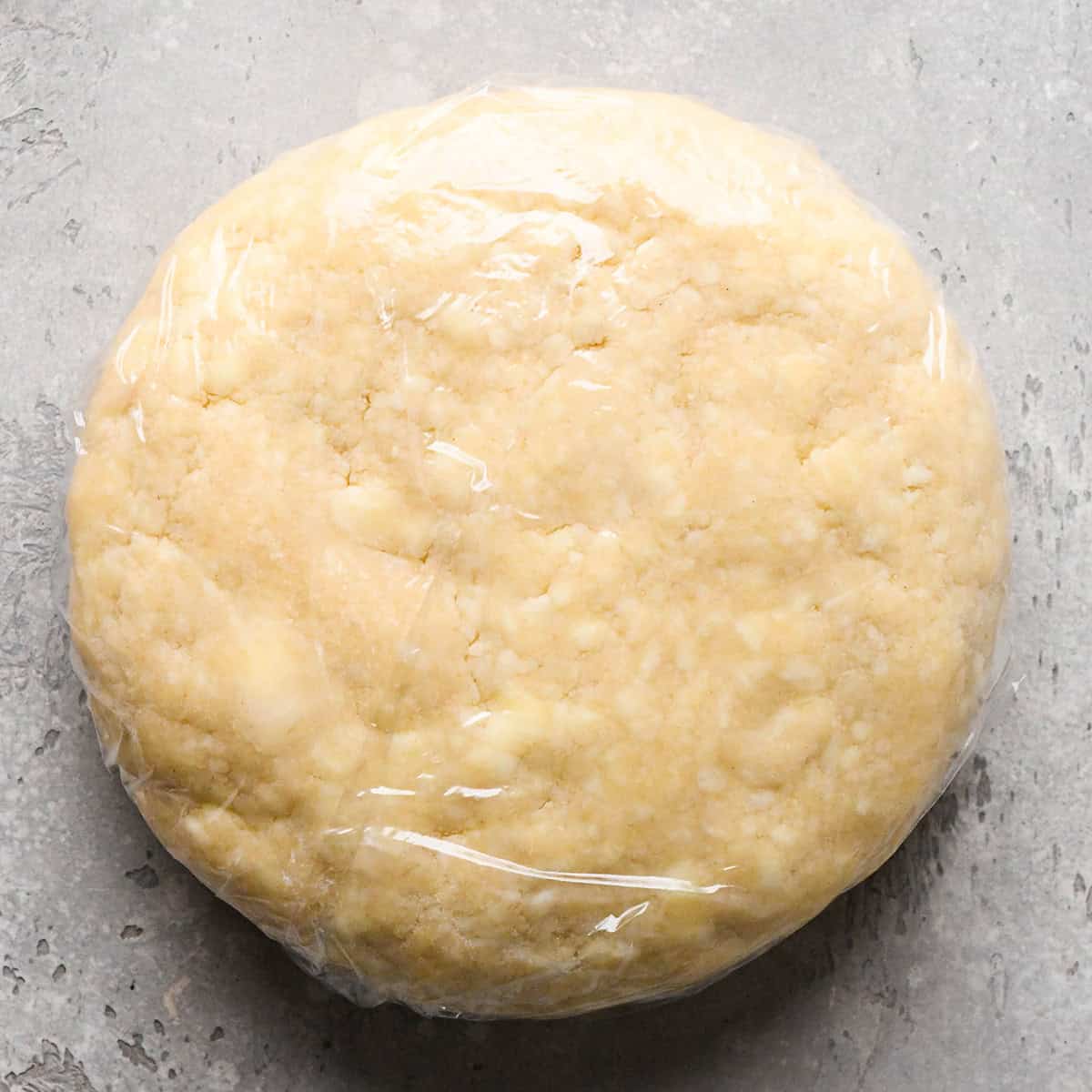 pie crust dough formed into a round disc wrapped in plastic wrap to make pie crust cookies