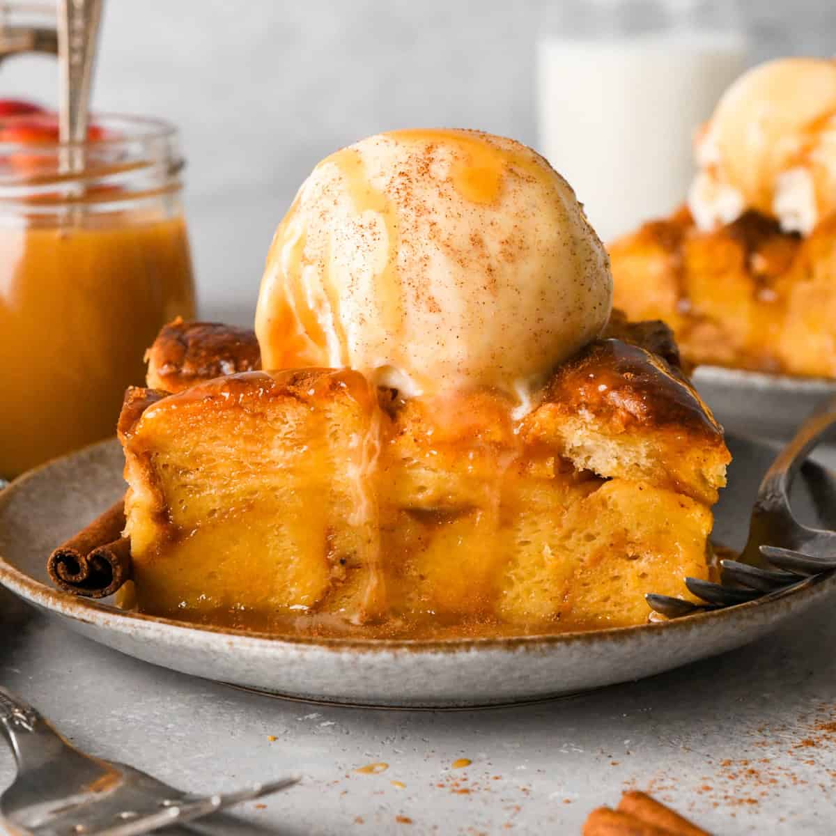 Pumpkin Bread Pudding on a plate topped with a scoop of vanilla ice cream, cinnamon and caramel sauce 