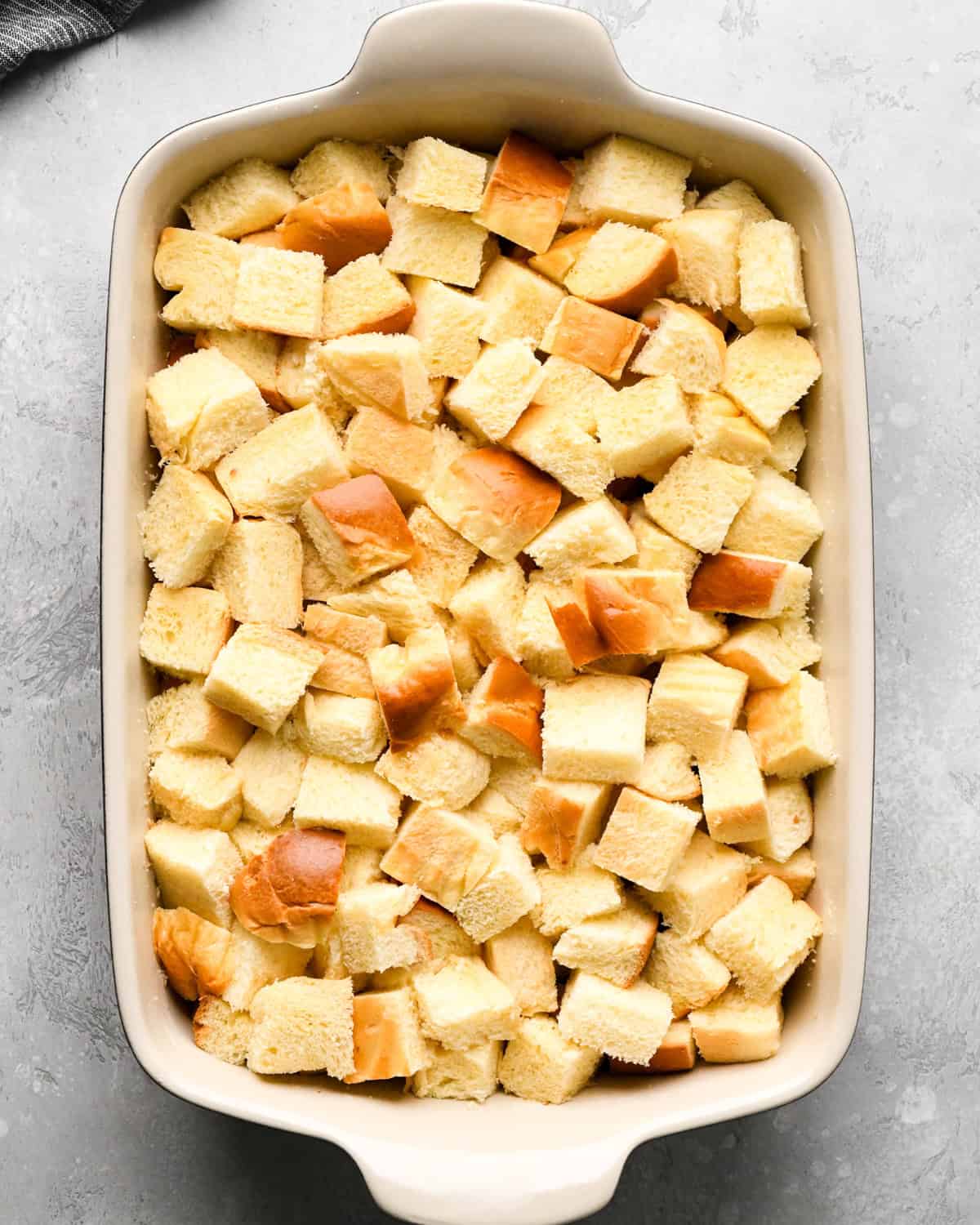 cubed brioche bread in a 9x13" baking dish making pumpkin bread pudding