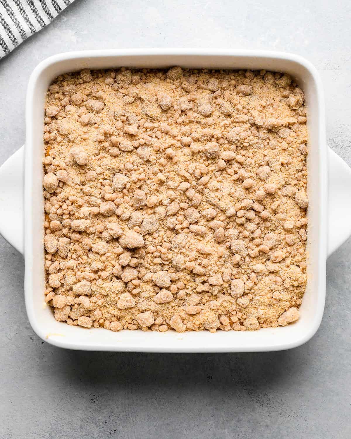crumb toping over pumpkin coffee cake batter in a baking dish before baking