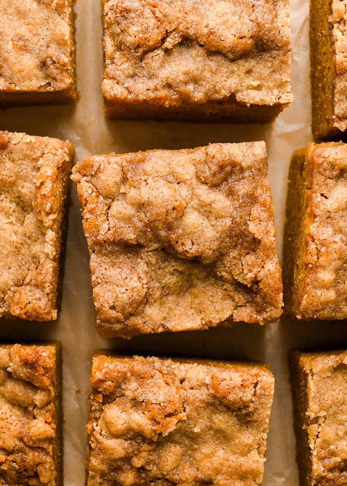 pumpkin coffee cake cut into 9 square pieces on parchment paper