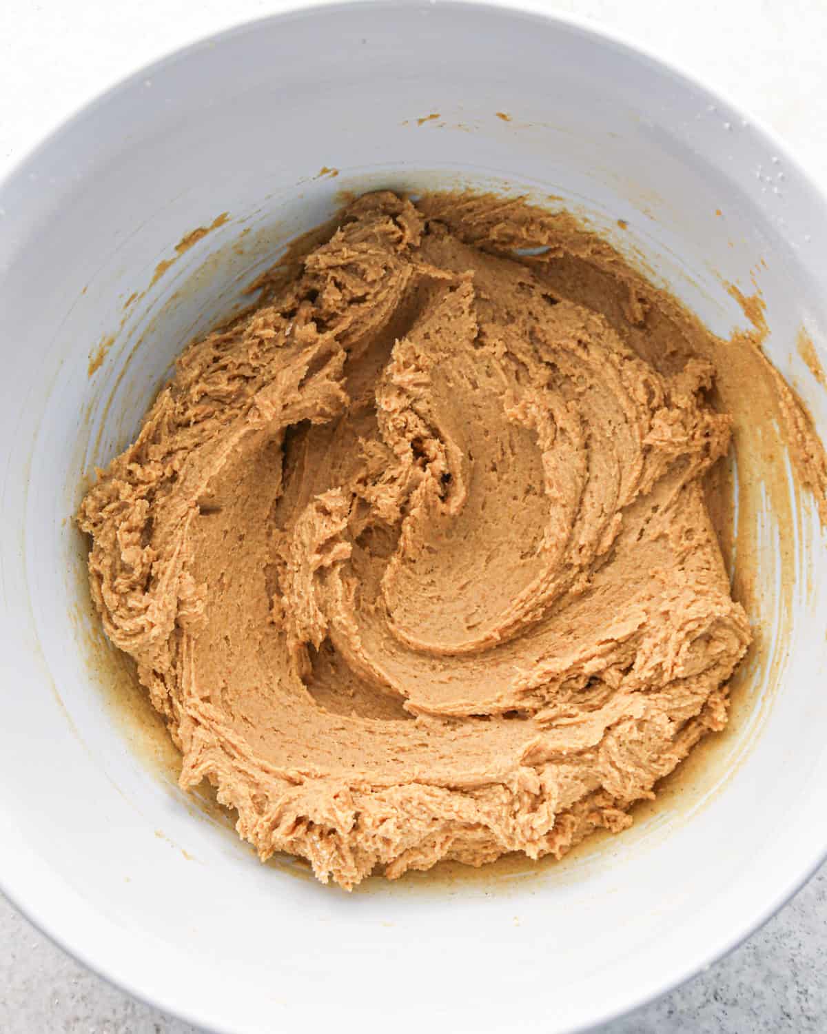 pumpkin snickerdoodle cookie dough in a white bowl on a gray surface