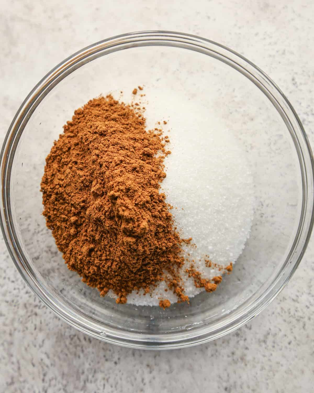 cinnamon and sugar in a glass bowl on a gray surface before mixing