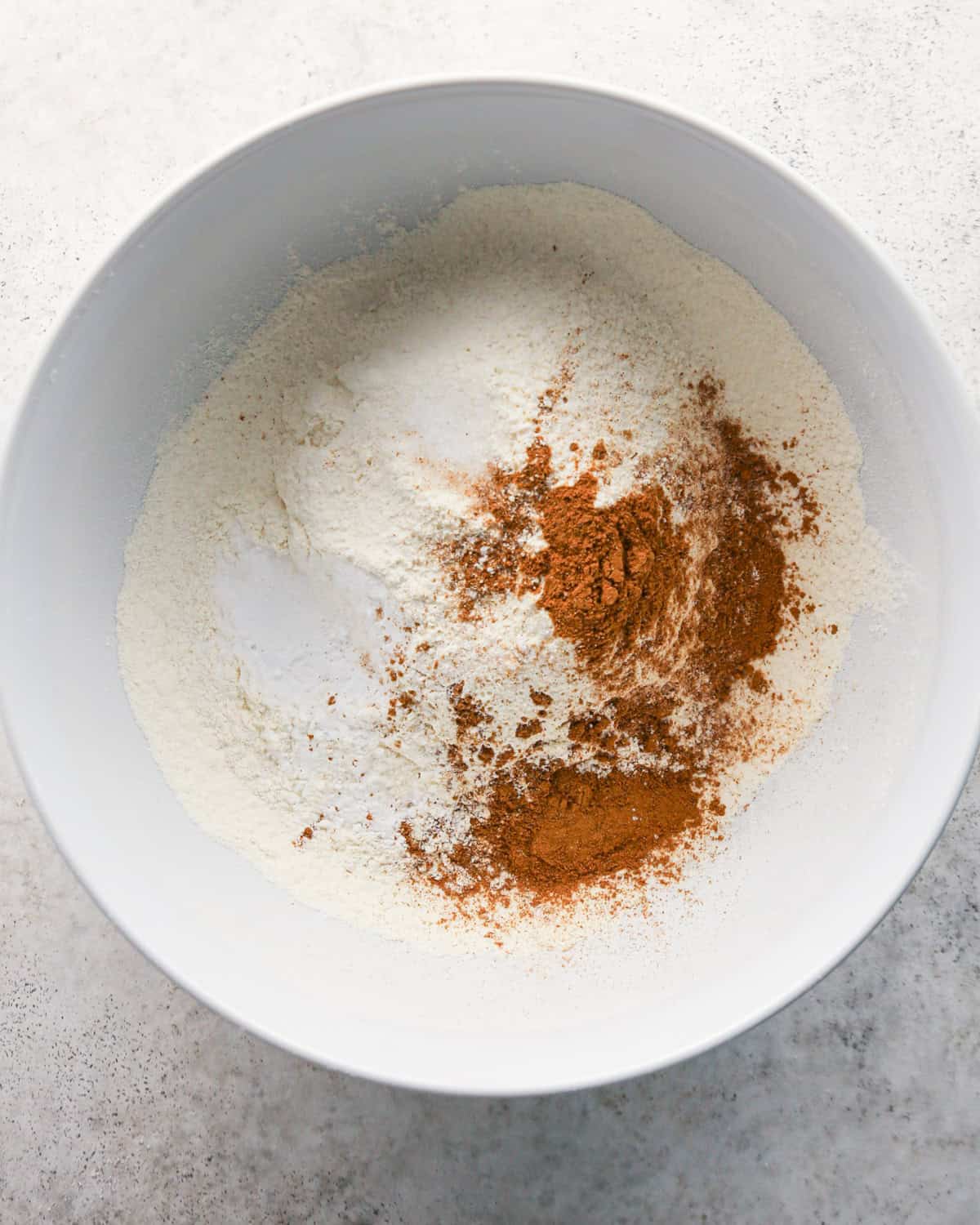 flour, salt, baking soda, baking powder, cinnamon an pumpkin pie spice in a white bowl before mixing making pumpkin snickerdoodles