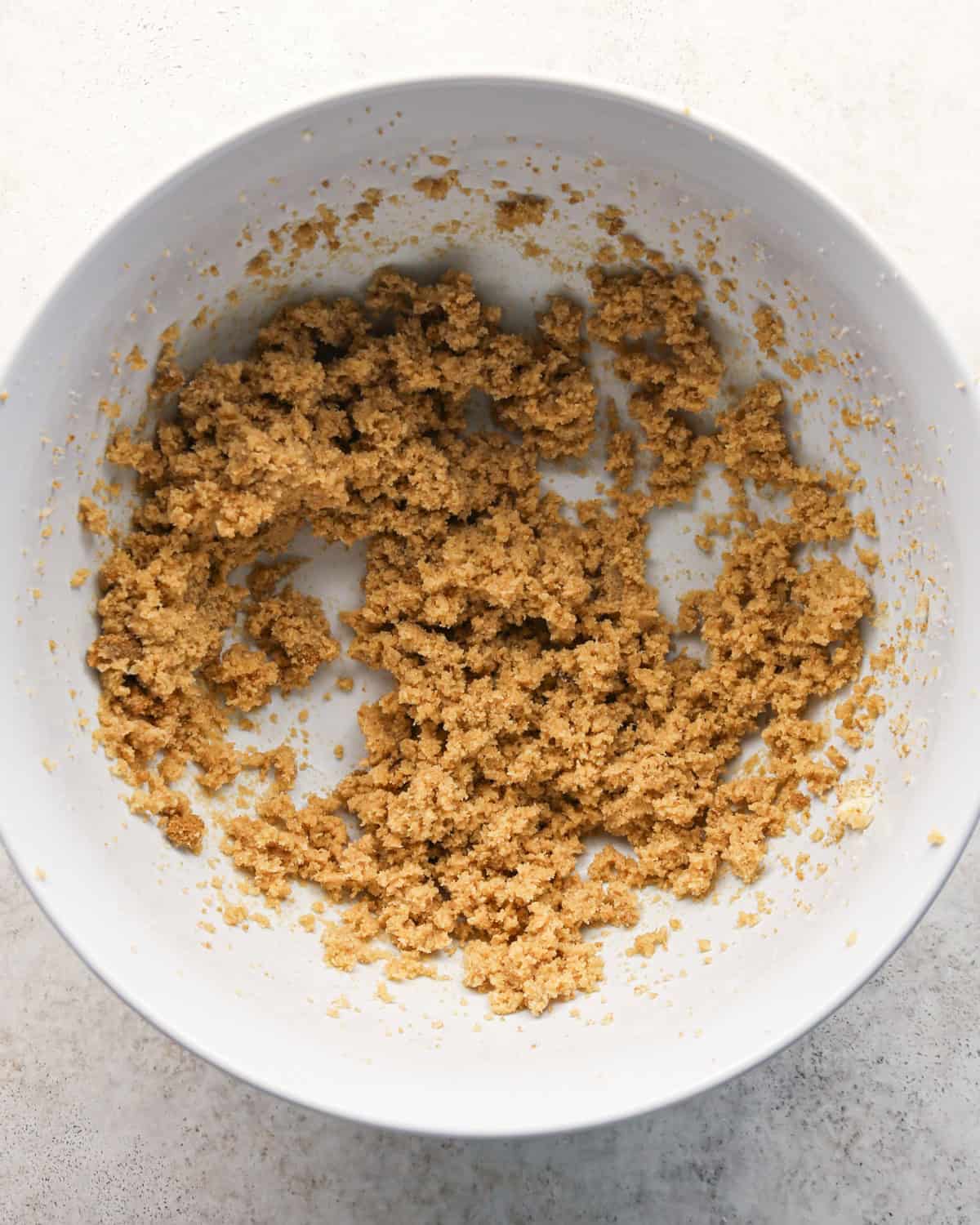 butter, brown sugar and white sugar in a white bowl on a gray surface after beating making pumpkin snickerdoodles