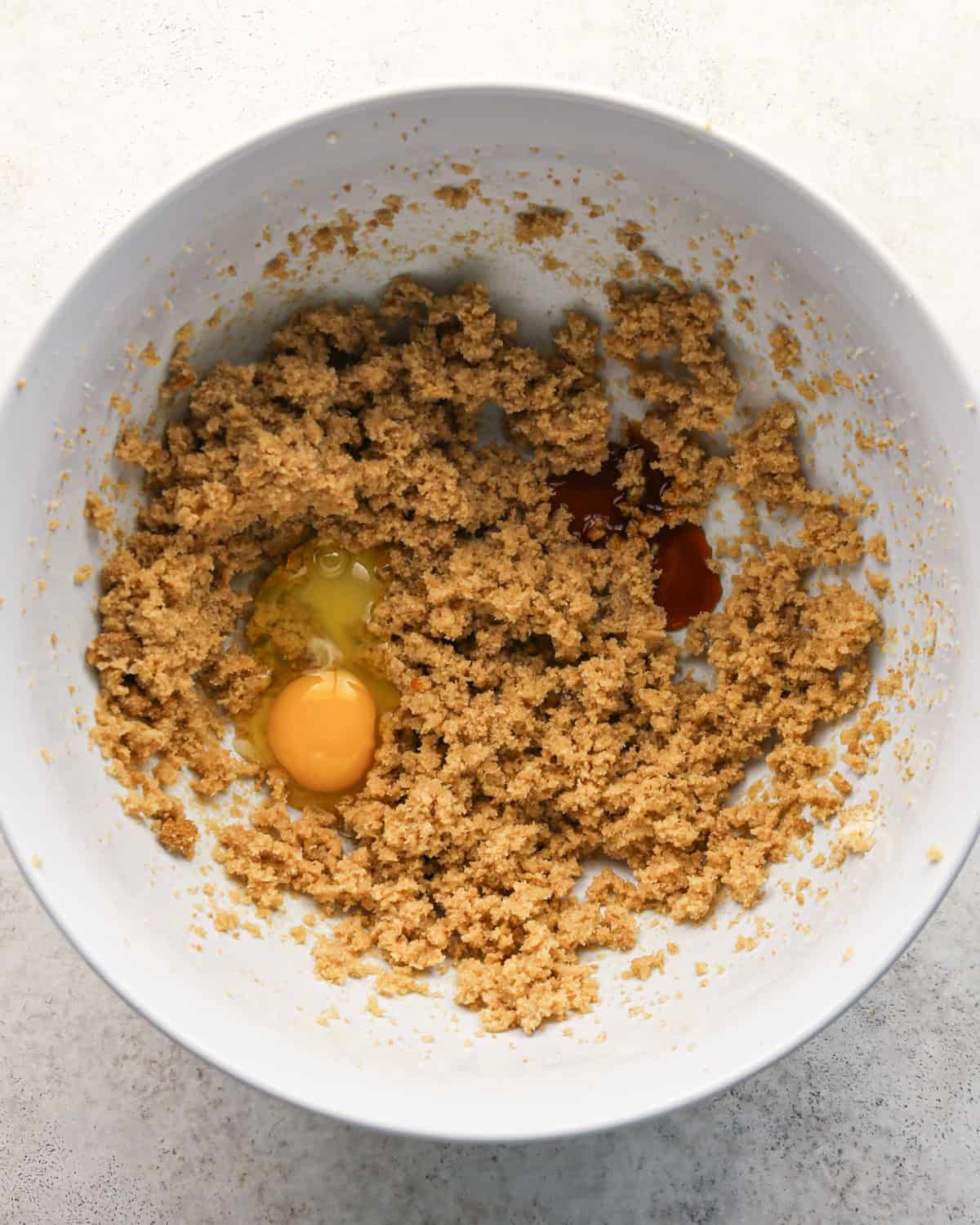 egg and vanilla added to the beaten butter and sugar mixture before mixing in a white bowl making pumpkin snickerdoodles