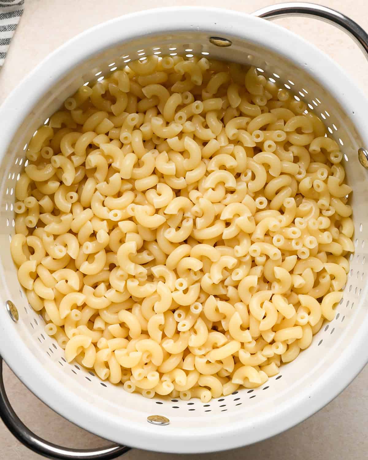 cooked macaroni noodles in a white colander to make bacon mac and cheese