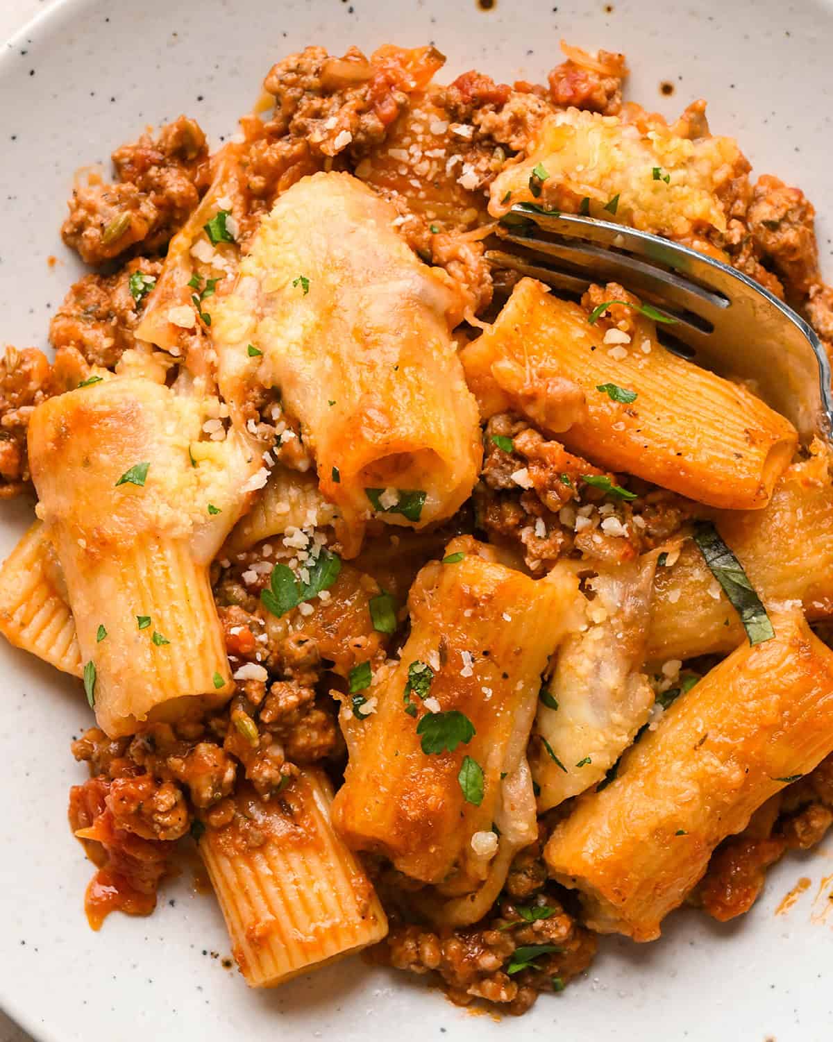 Baked Ziti on a plate garnished with parmesan cheese and parsley, with a fork