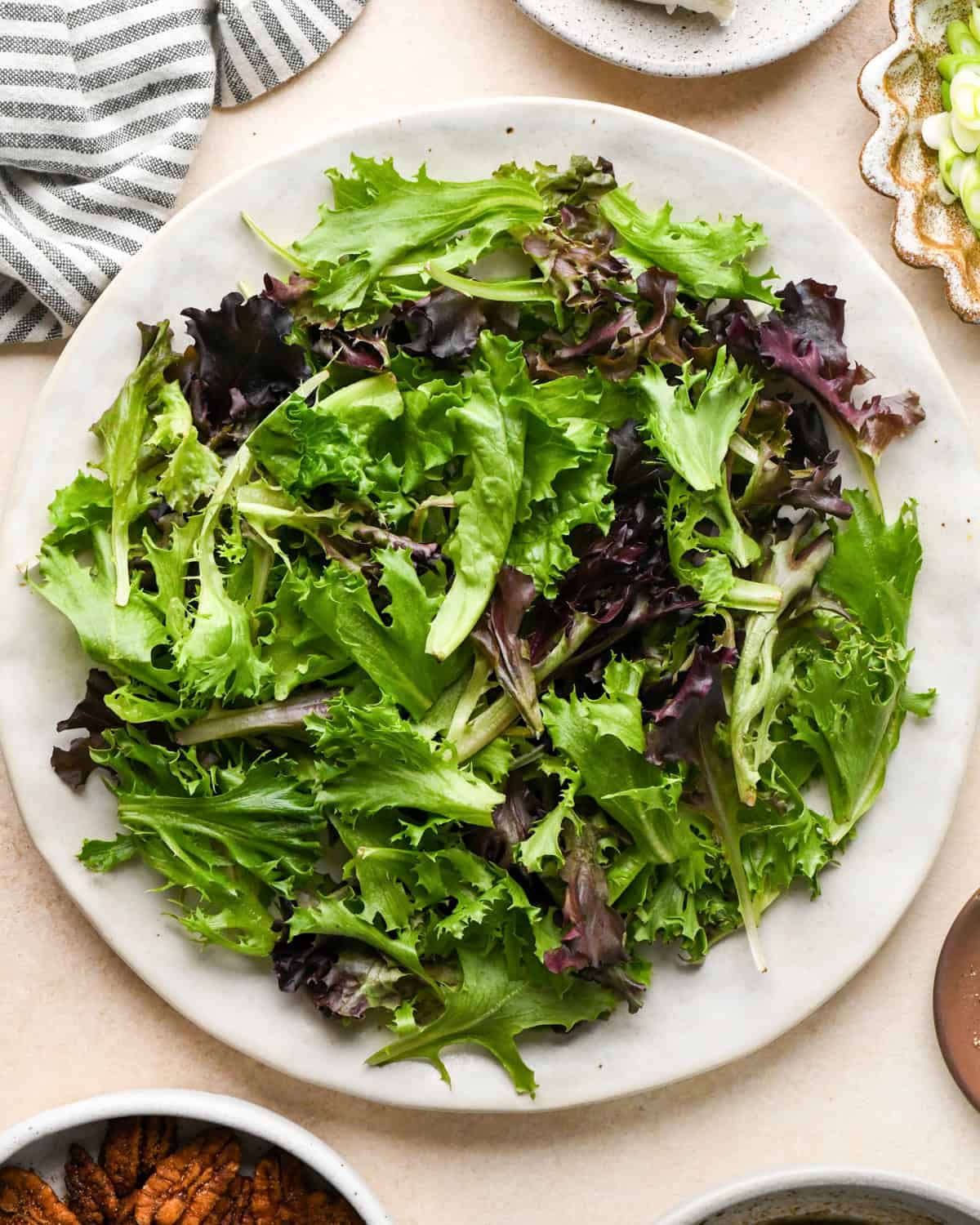 assembling beet salad - spring mix on a white ceramic plate