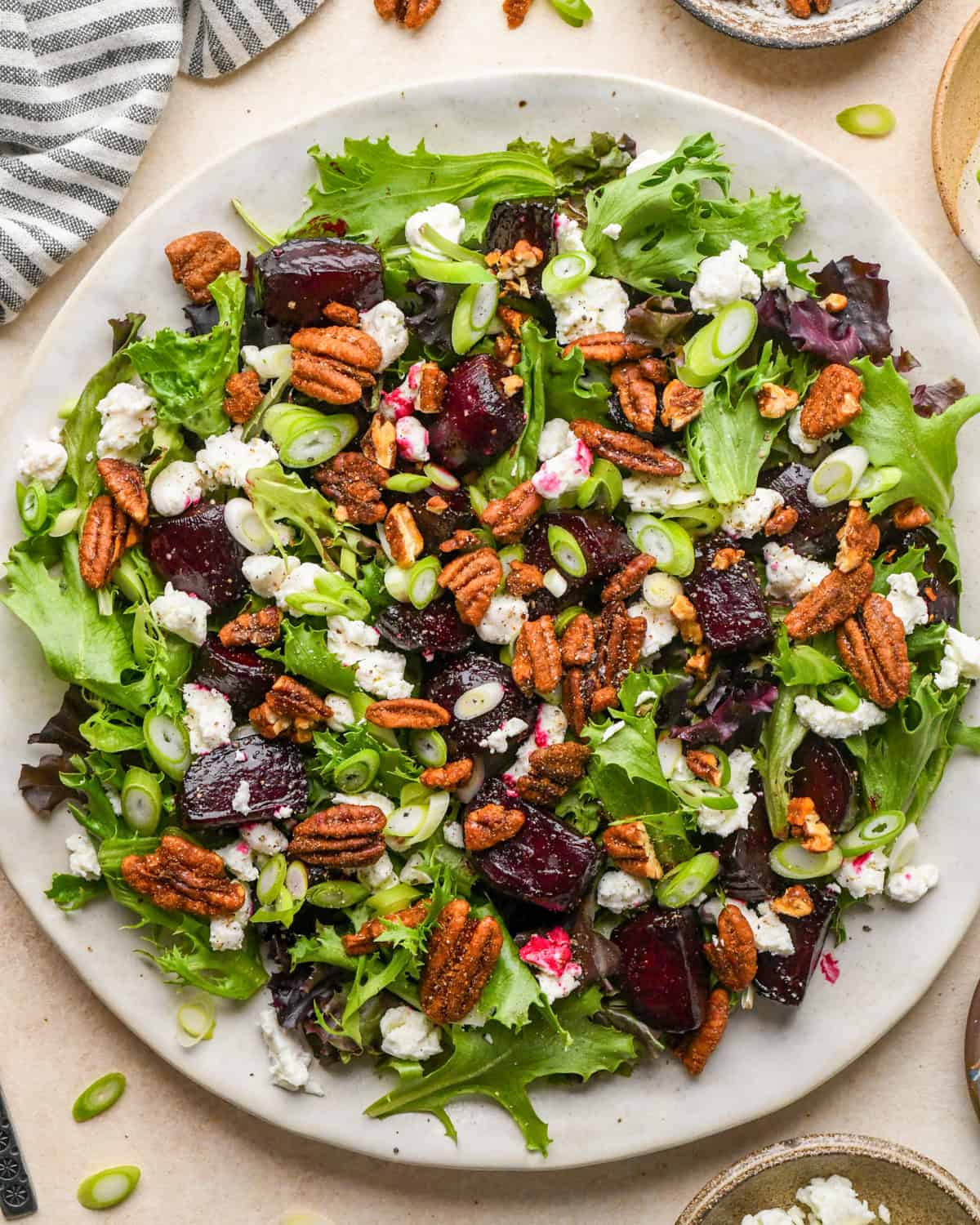 assembling beet salad - pecans added on top of the other ingredients