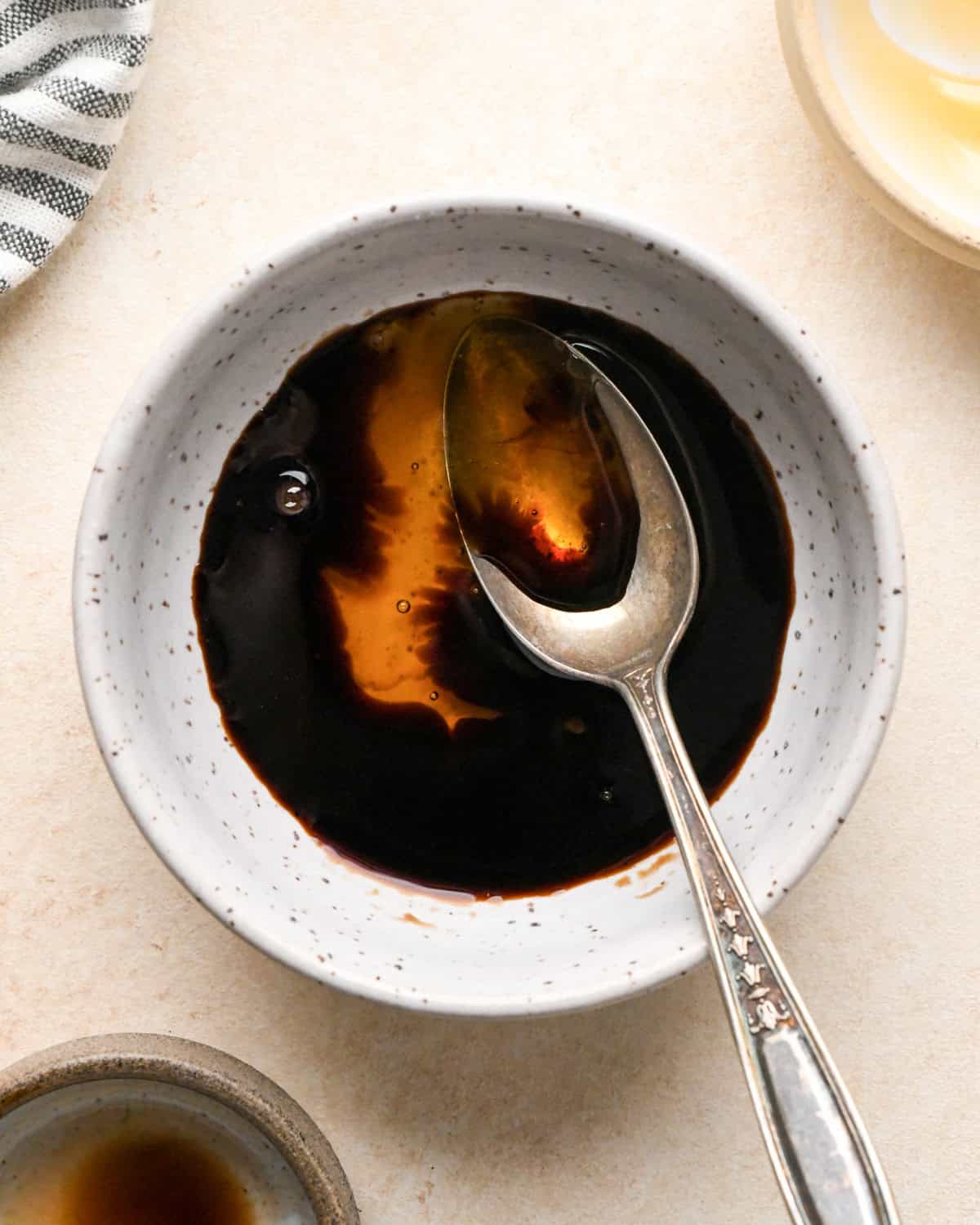 balsamic vinegar and honey in a white speckled ceramic bowl with a sliver spoon before mixing to use on roasted beets to put in a beet salad