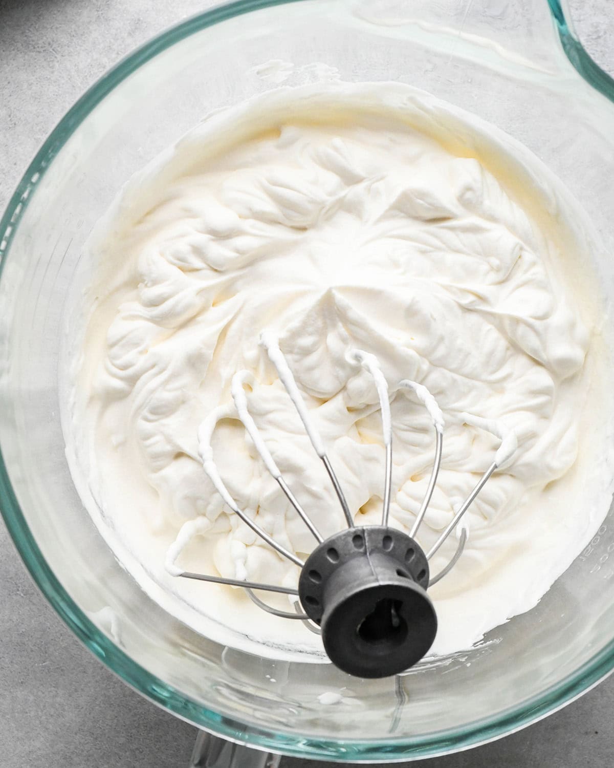 whipped cream in a glass mixing bowl with the wire whisk attachment to be used as the topping for chocolate peanut butter pie