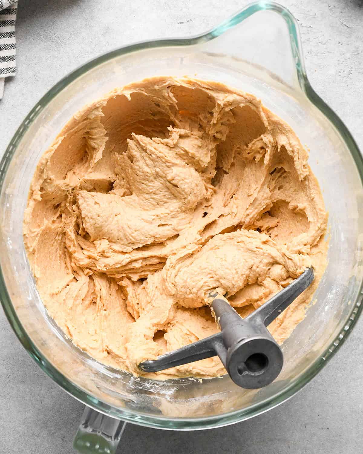 chocolate peanut butter pie filling in a glass mixing bowl with the paddle attachment on a gray surface