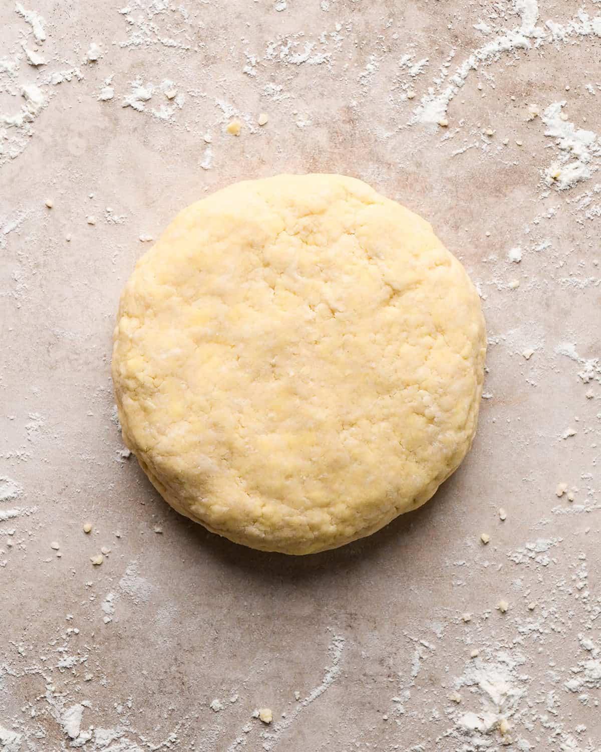 a disc of pie dough on a light brown well-floured surface
