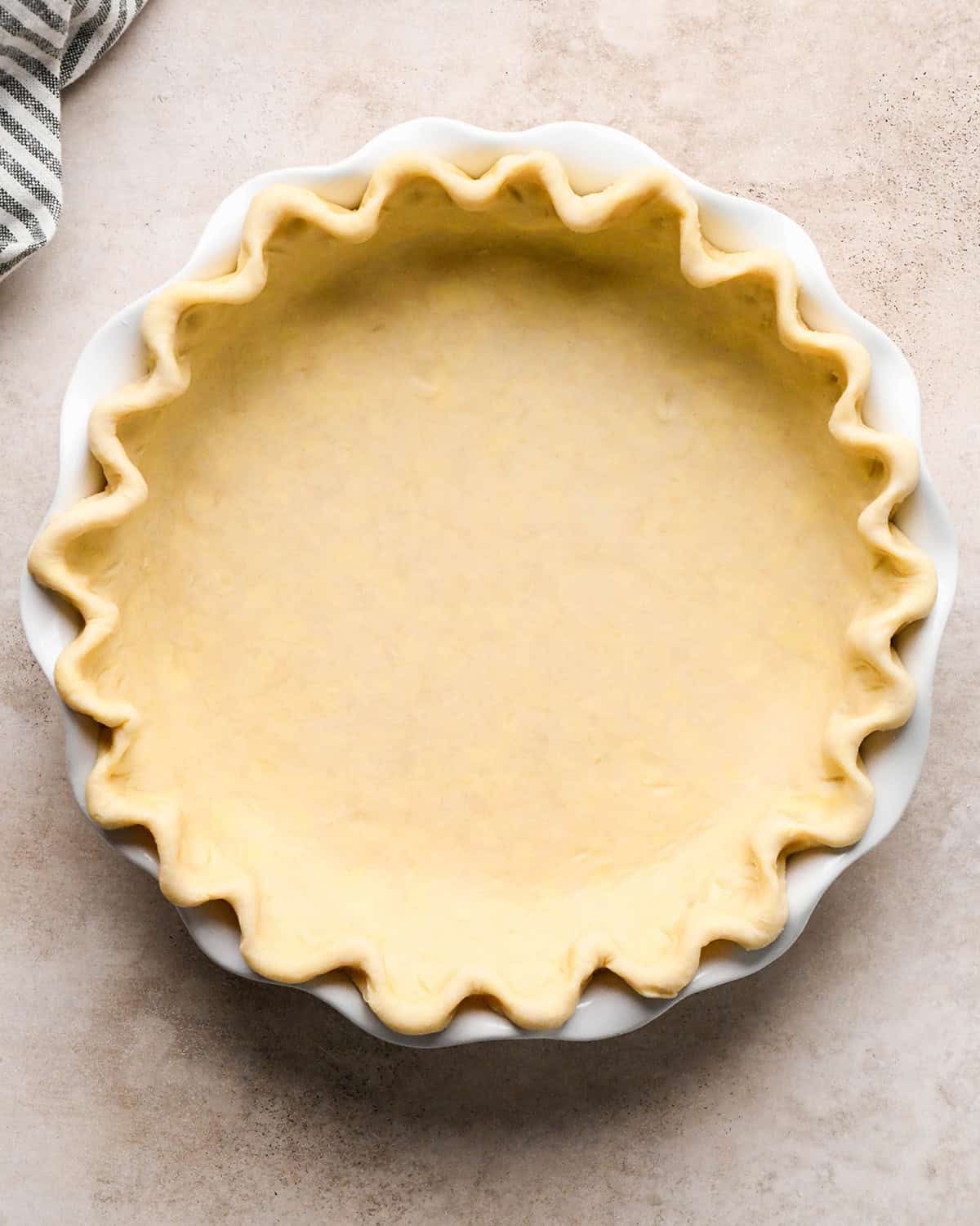 a pie crust with a fluted edge in a white ceramic pie dish to make dutch apple pie