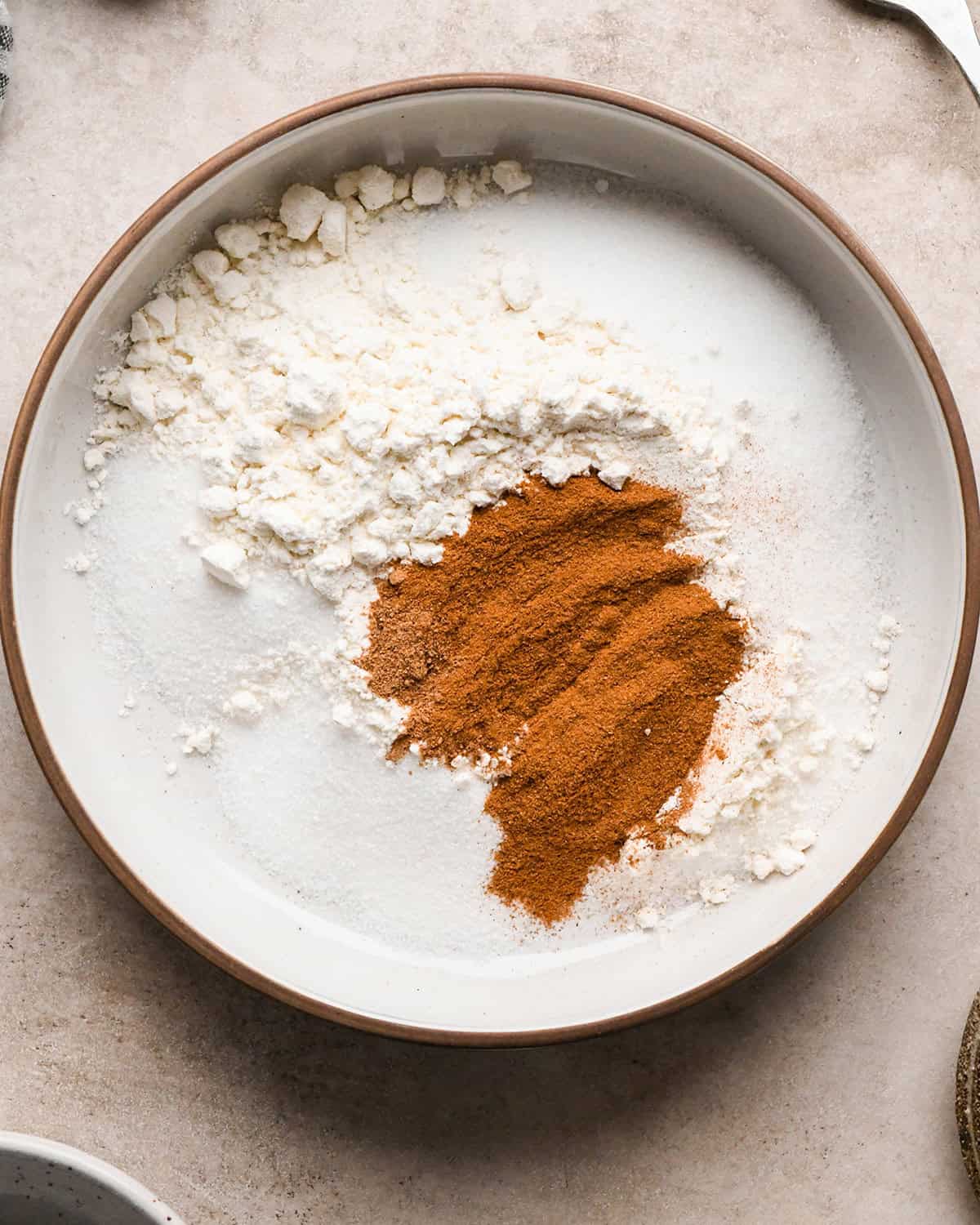 flour, sugar, cinnamon nutmeg and salt in a bowl on a tan surface before mixing making the dutch apple pie filling.