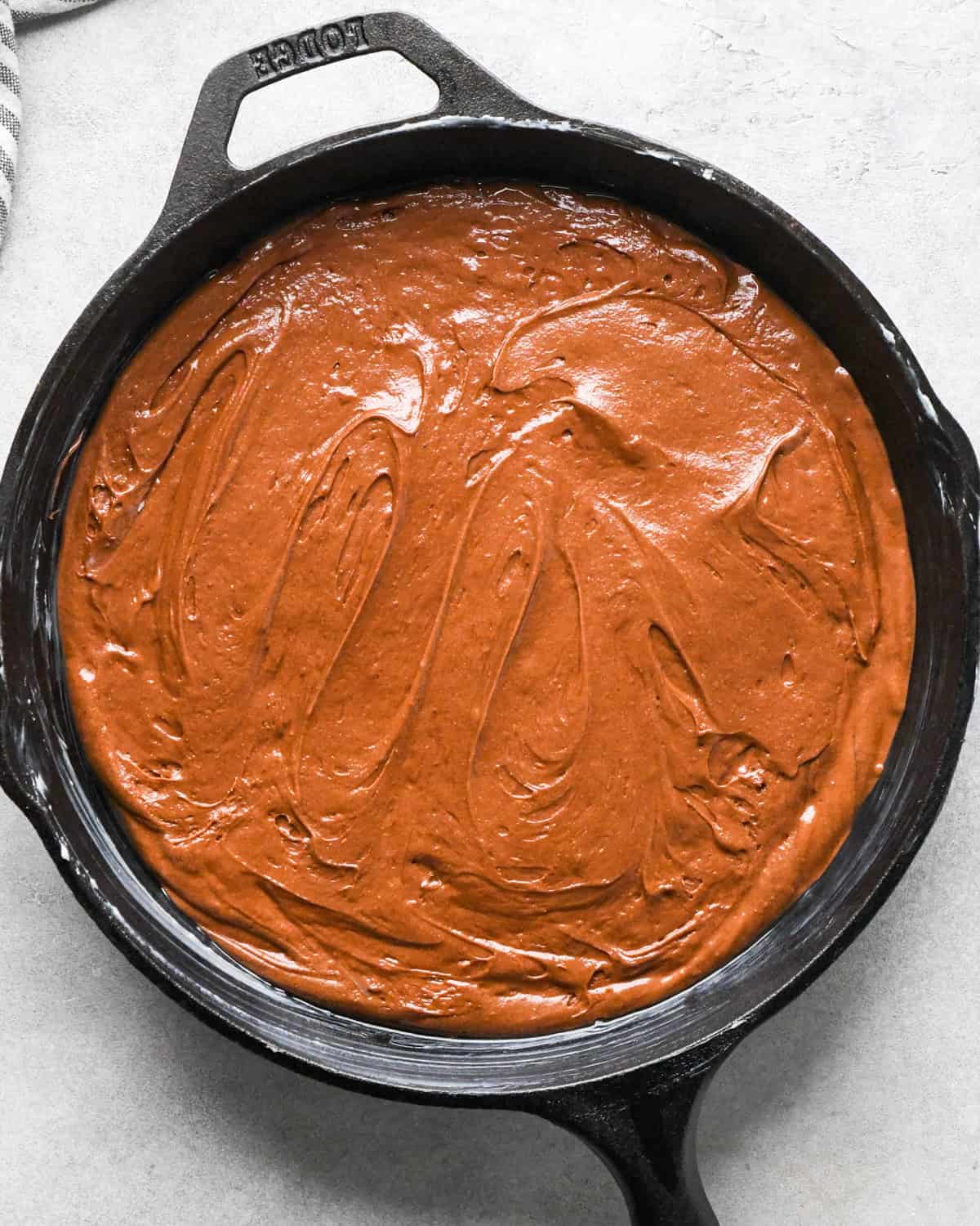 Making skillet brownies - brownie mixture is poured into a black, buttered cast iron skillet and spread evenly
