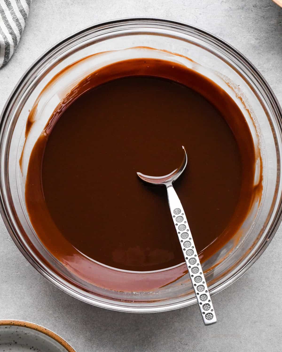 Making skilled brownies - melted chocolate and butter in a clear glass bowl being stirred with a spoon