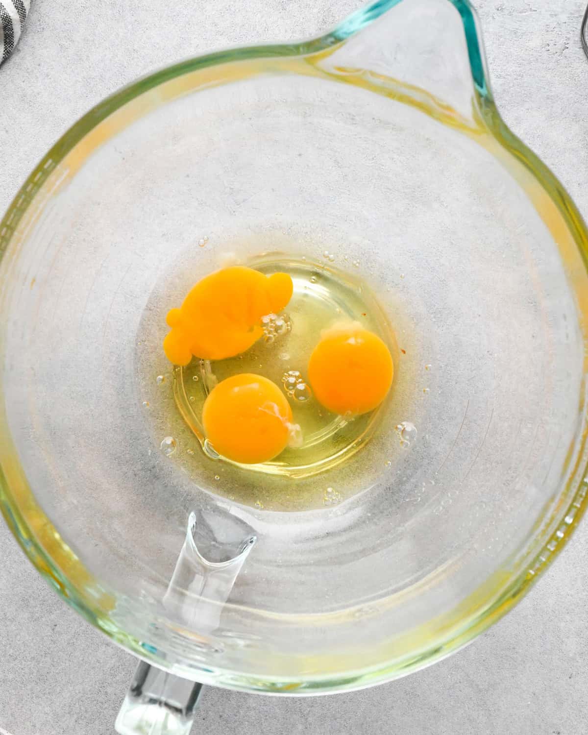 Making skillet brownies - 3 eggs cracked into a clear measuring bowl on a countertop