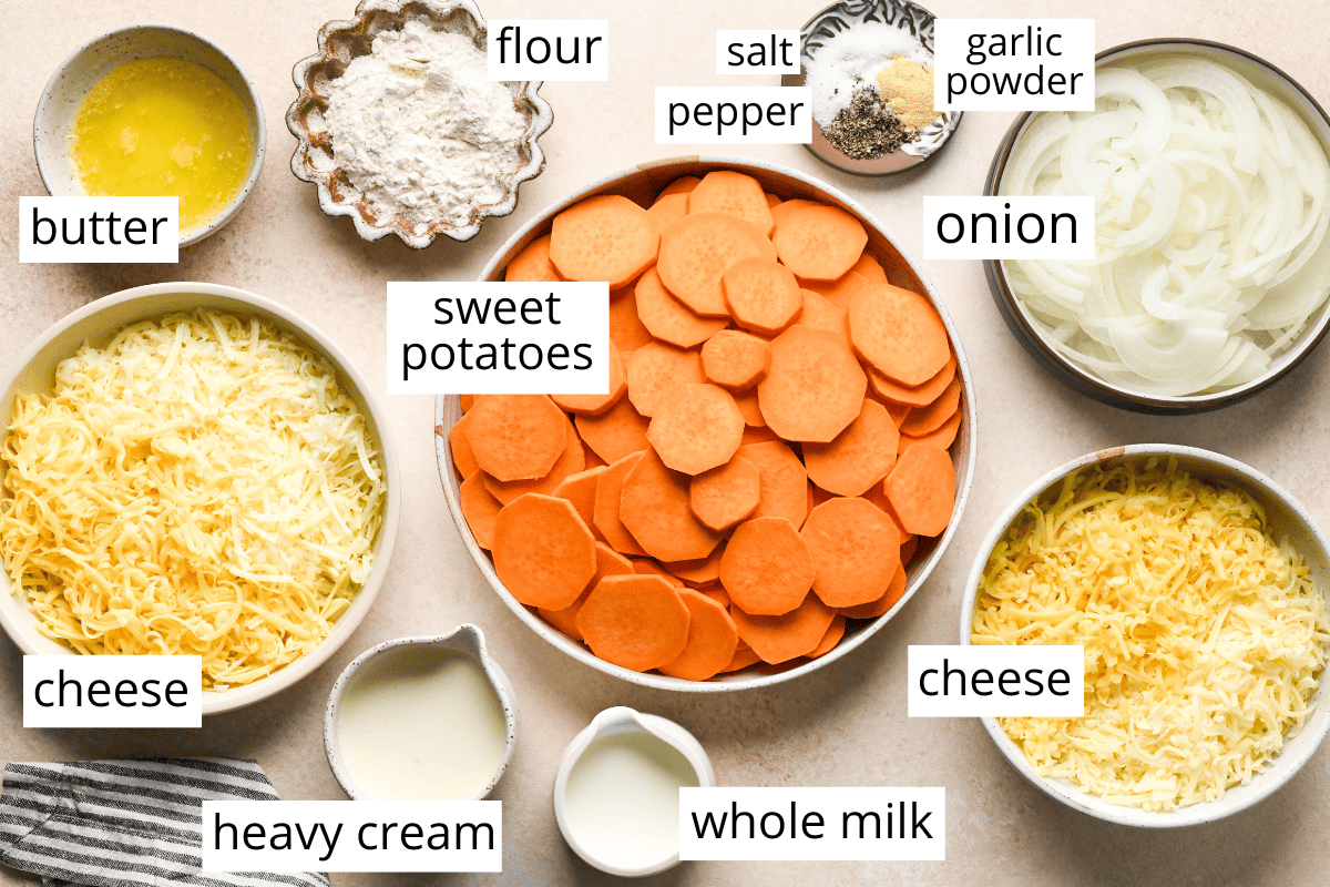 the ingredients in this sweet potato gratin recipe in bowls and labeled like sweet potatoes, onion, cheese, butter, flour, heavy cream, milk, salt and pepper