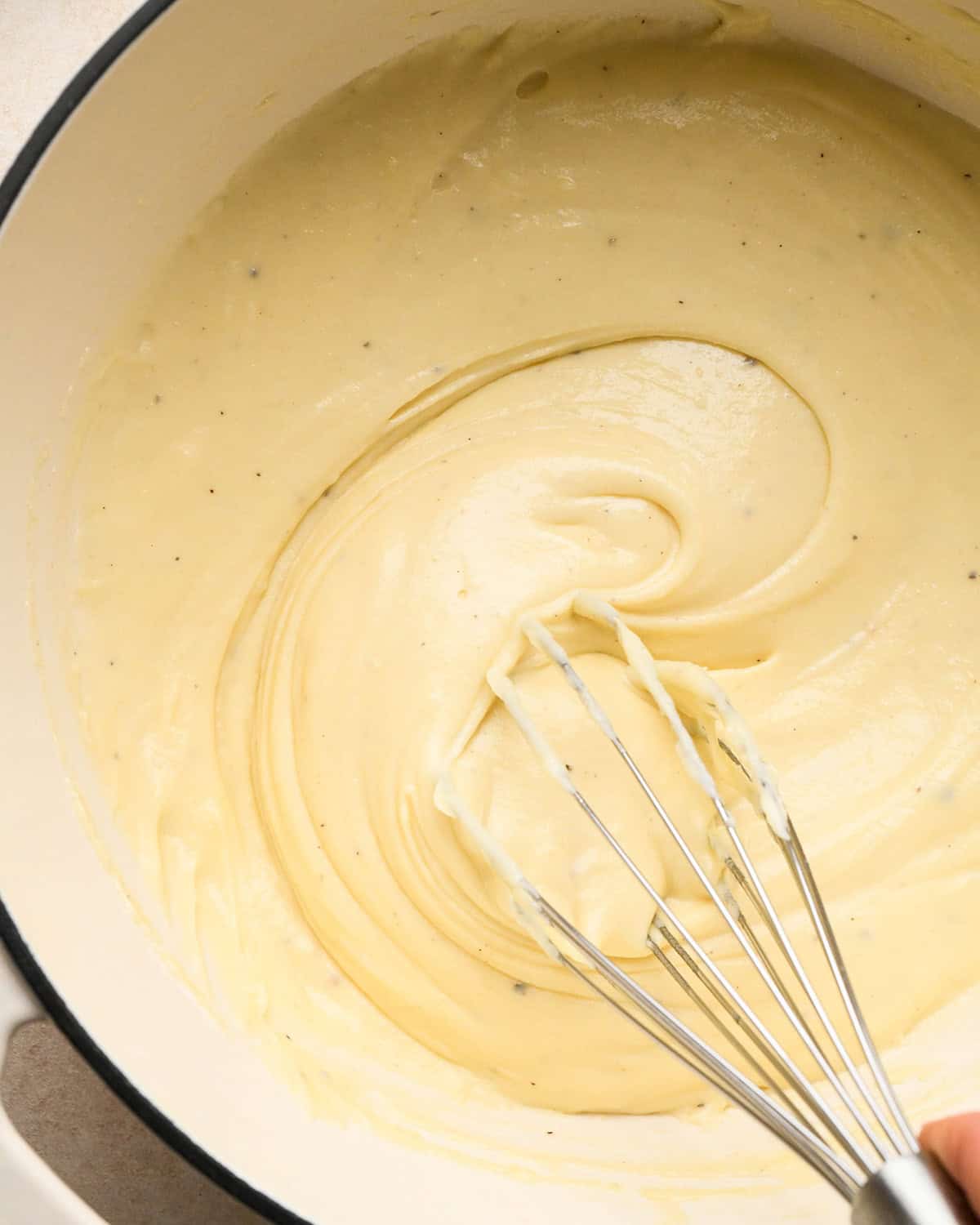 making sweet potato gratin - a whisk whisking the cheese sauce