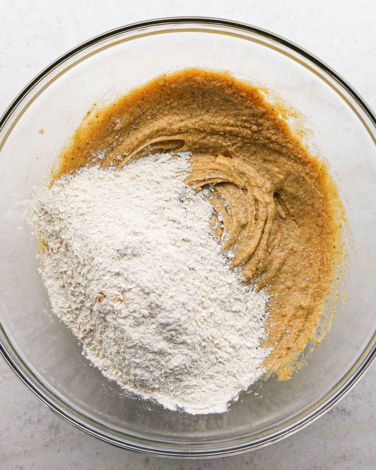 Making brown butter oatmeal cookies - overhead photo of wet and dry ingredients being combined in a clear bowl.