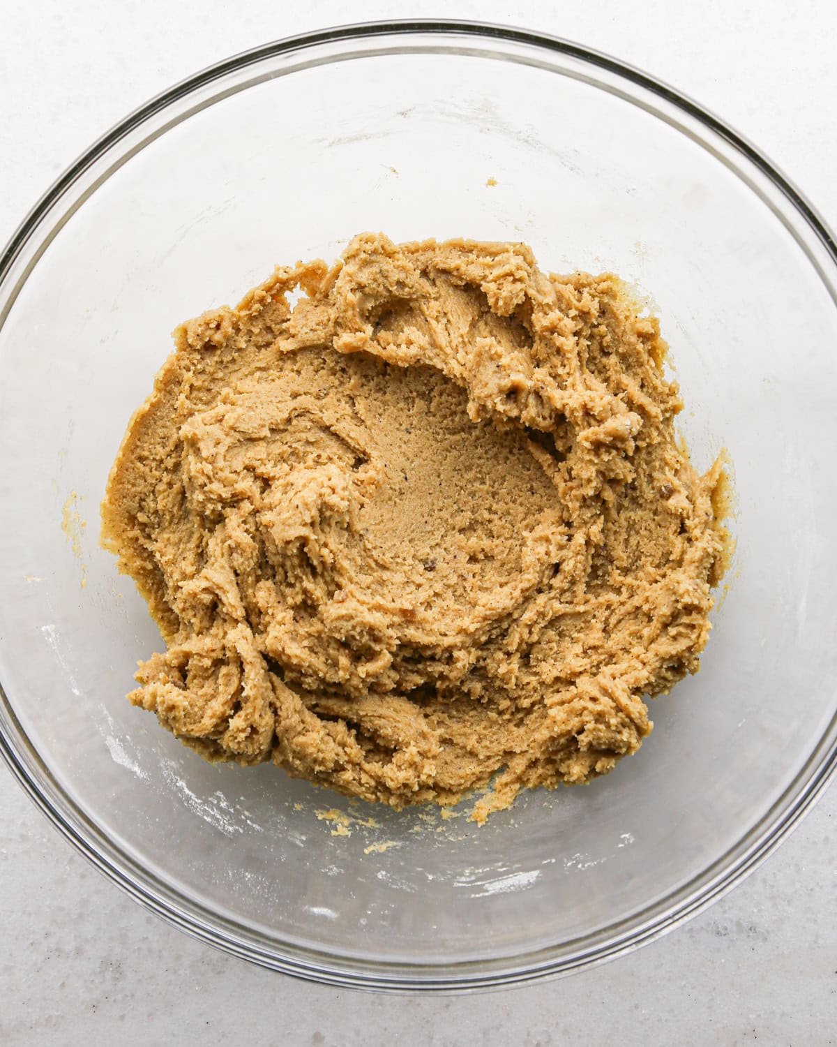 Making brown butter oatmeal cookies - overhead photo of wet and dry ingredients being mixed together in a clear bowl.