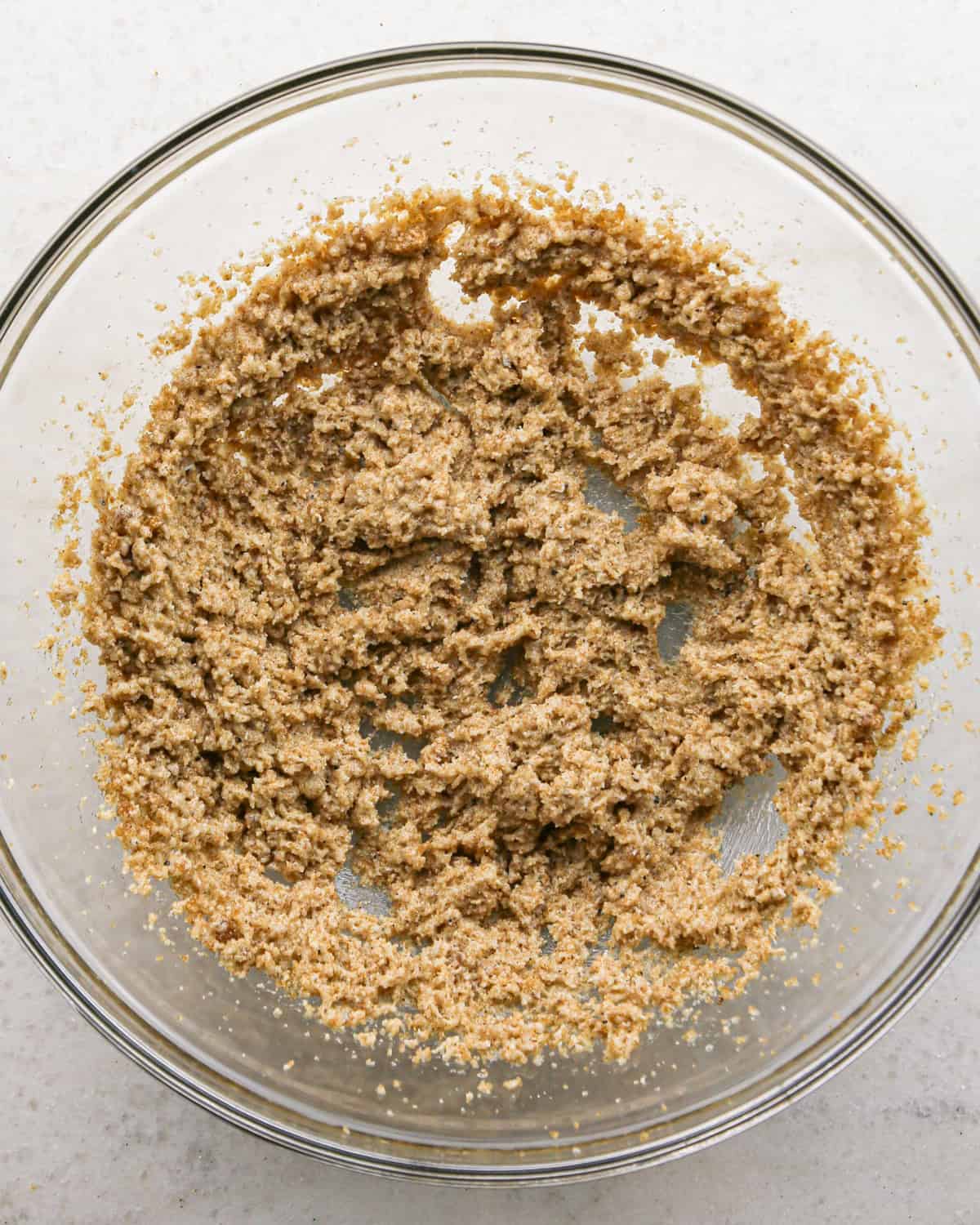 Making brown butter oatmeal cookies - overhead photo of brown butter, sugar, and brown sugar being added to a clear mixing bowl and mixed together.