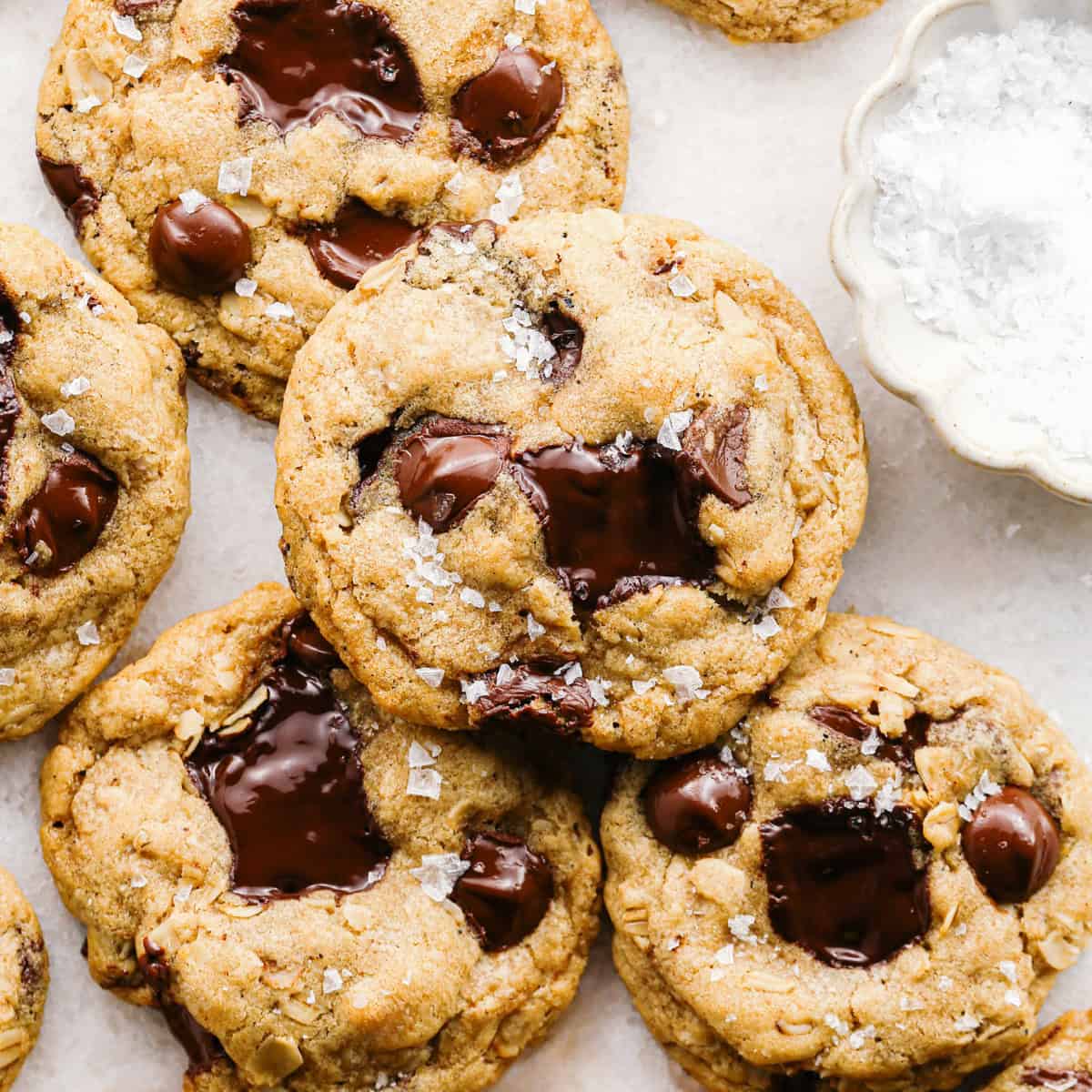 Close-up photo of brown butter oatmeal cookies with melted chocolate chunks and a sprinkle of flaky sea salt on top.