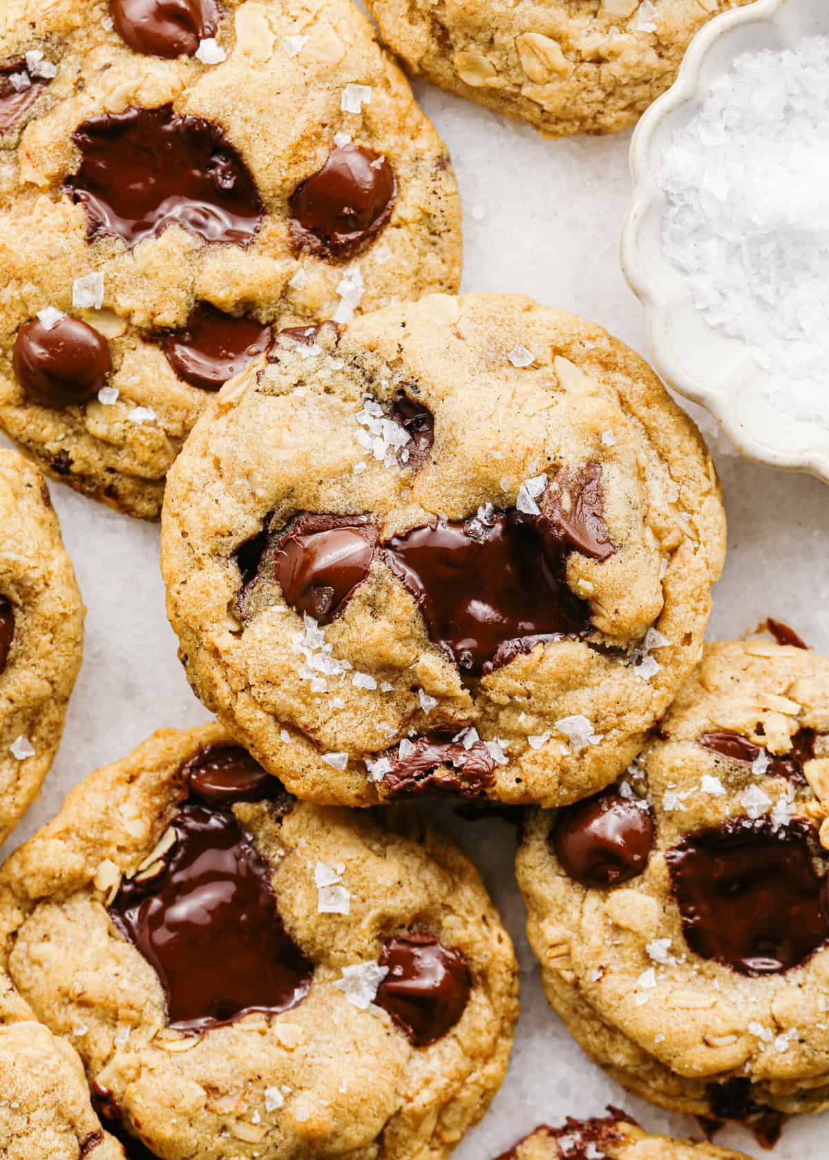 Close-up photo of brown butter oatmeal cookies with melted chocolate chunks and a sprinkle of flaky sea salt on top.