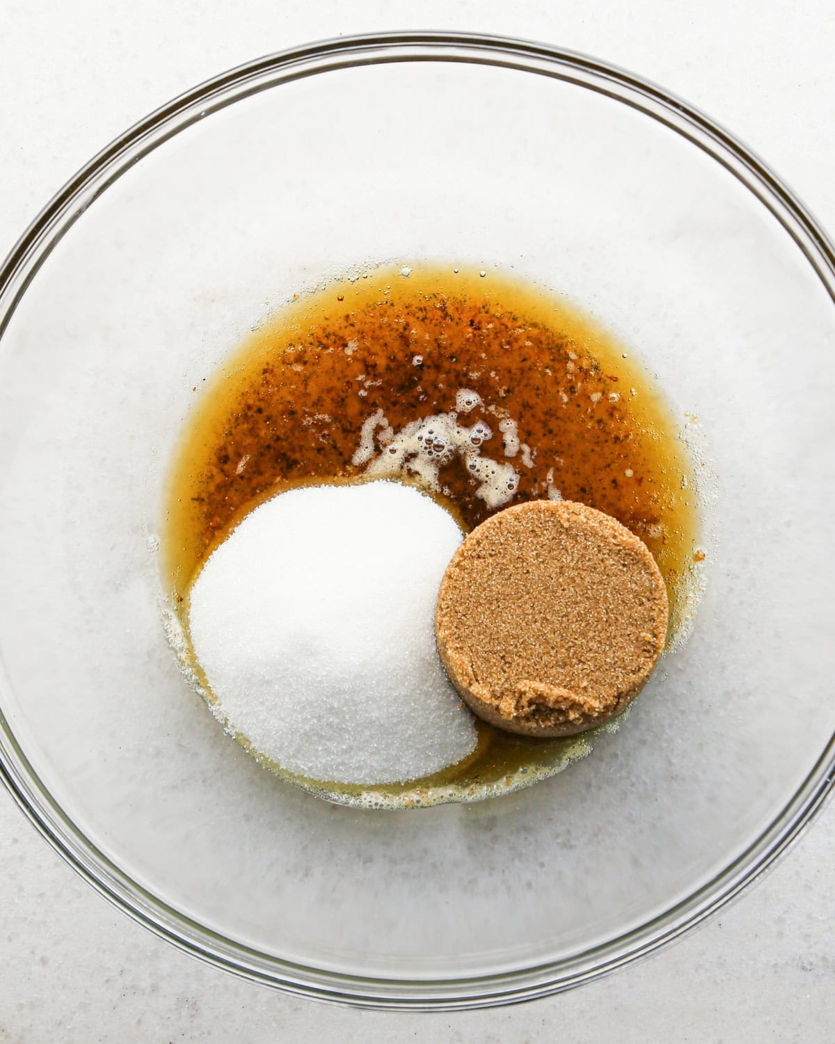 Making brown butter oatmeal cookies - overhead photo of brown butter, sugar, and brown sugar being added to a clear mixing bowl.
