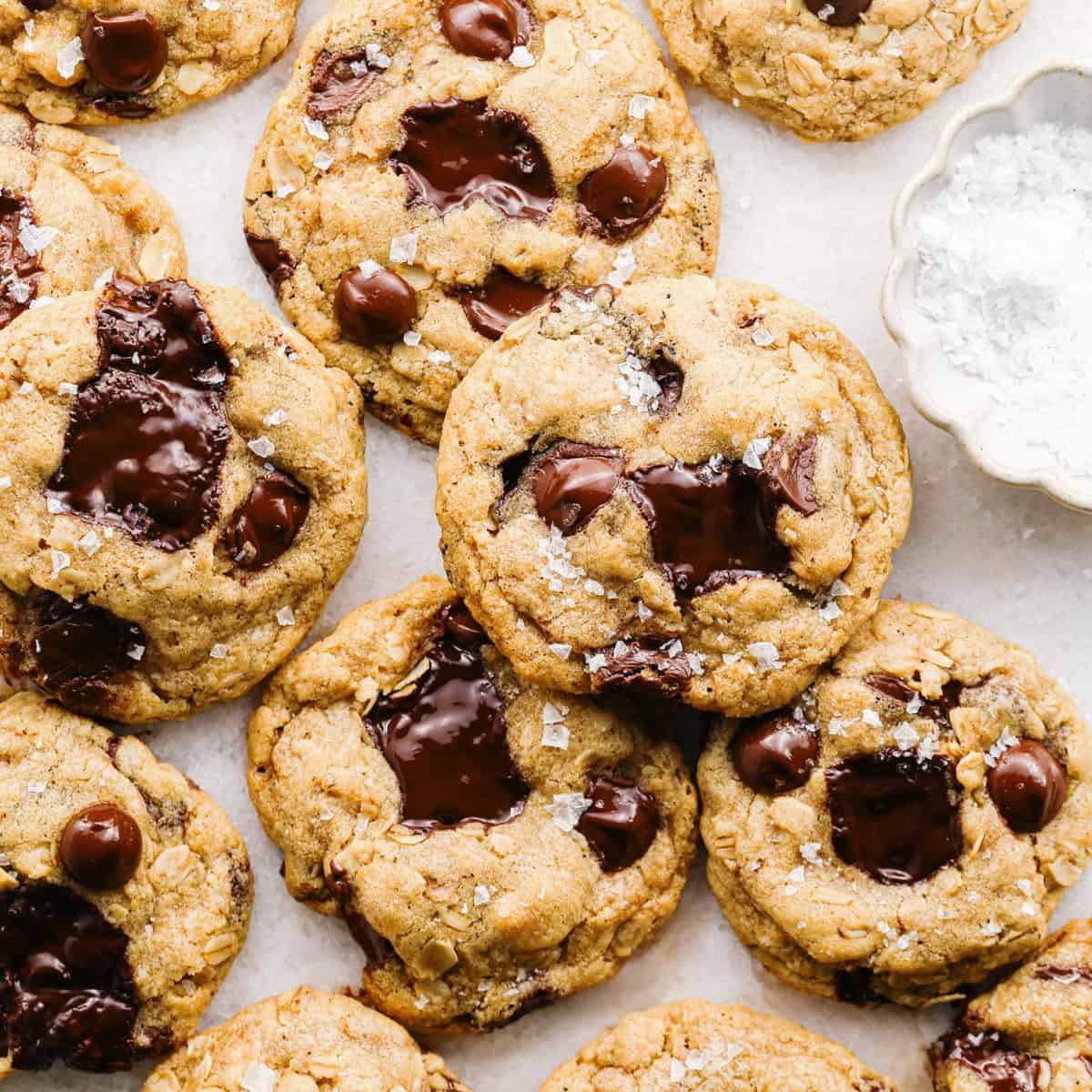 Overhead photo of brown butter oatmeal cookies with melted chocolate chunks and a sprinkle of flaky sea salt on top.