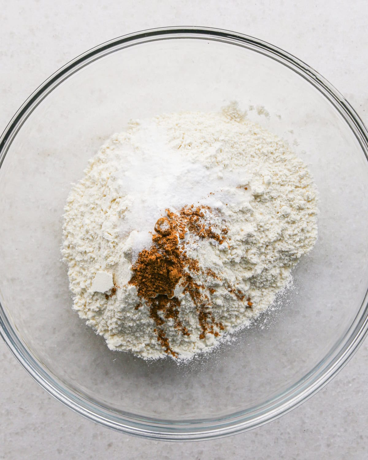 Making brown butter oatmeal cookies - overhead photo of dry ingredients being added to a clear mixing bowl.