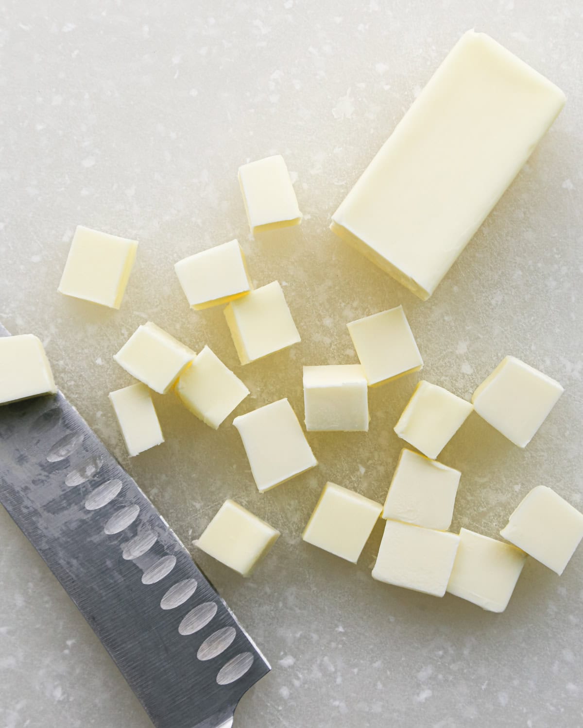 Making brown butter oatmeal cookies - overhead photo of a stick of cold butter being chopped into cubes with a knife.