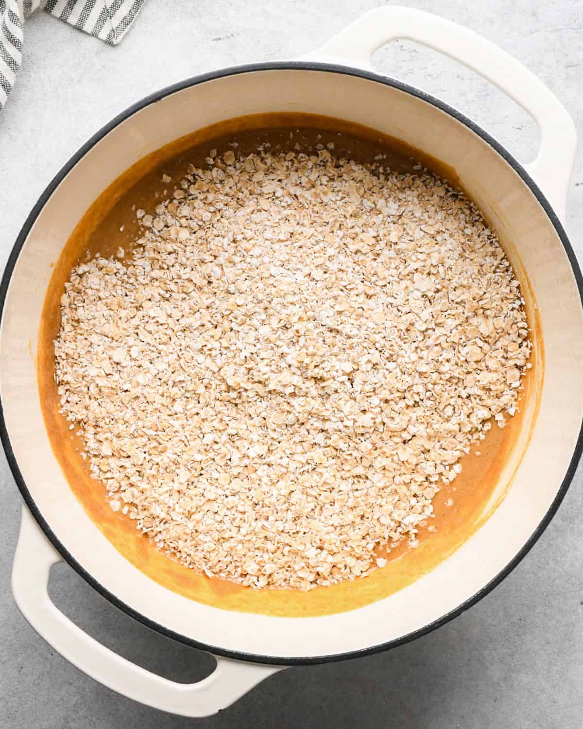 Making peanut butter oatmeal bars - overhead photo of quick-cooking oats being added to wet ingredients.