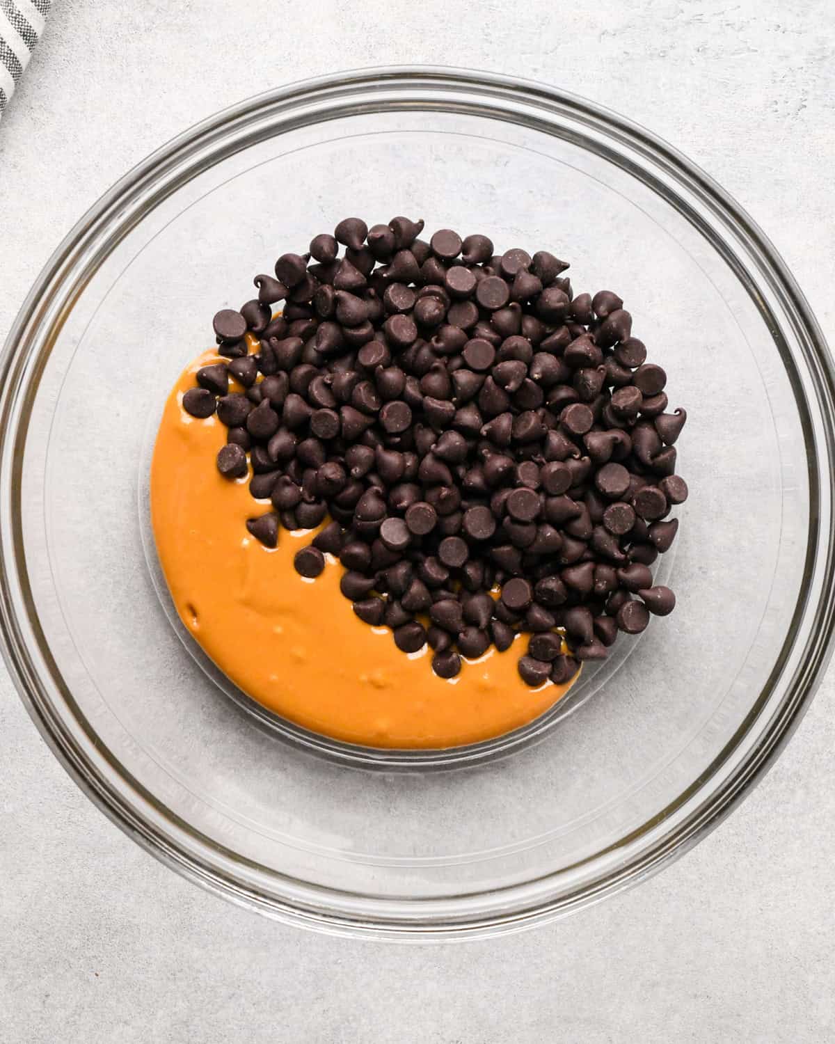 Making peanut butter oatmeal bars - overhead photo of peanut butter and semisweet chocolate chips in a clear mixing bowl.