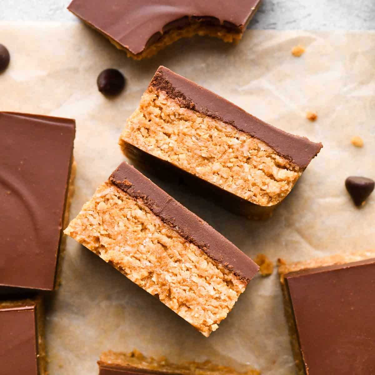 Overhead photo of peanut butter oatmeal bars with a chocolate peanut butter topping, cut into squares and sitting on parchment paper.