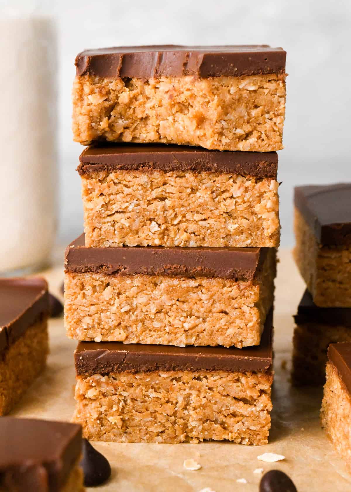 Close-up image of 4 chocolate peanut butter oatmeal bars stacked on top of each other, with a bite taken out of the top bar.