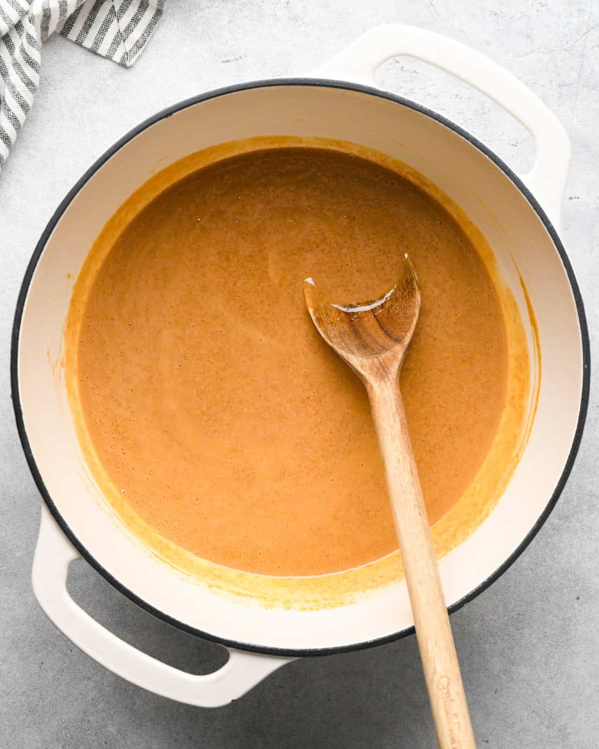 Making peanut butter oatmeal bars - overhead photo of butter, peanut butter, sea salt, and brown sugar in a pot and being stirred with a wooden spoon.