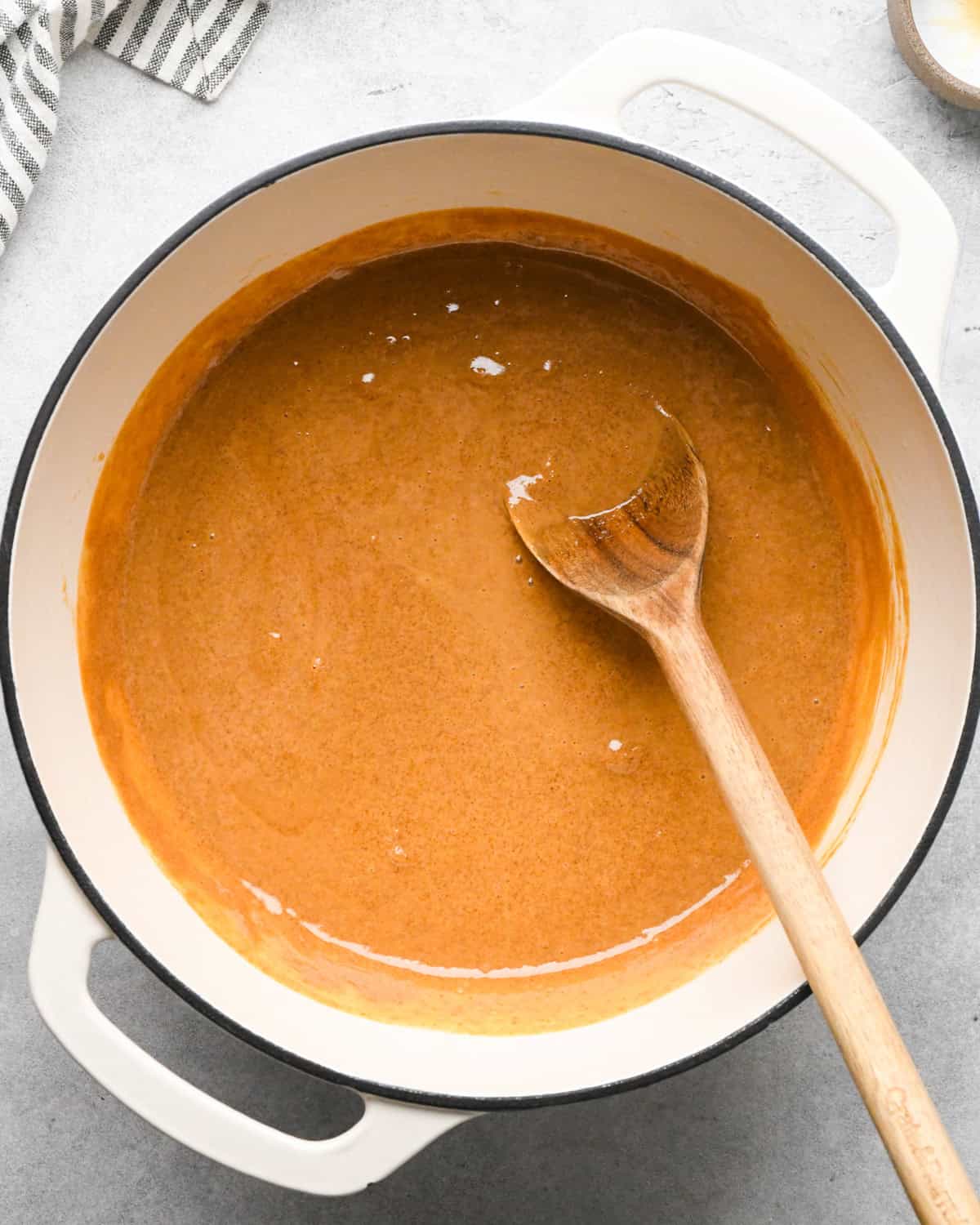 Making peanut butter oatmeal bars - overhead photo of butter, peanut butter, sea salt, brown sugar, and vanilla in a pot, being stirred together with a wooden spoon.