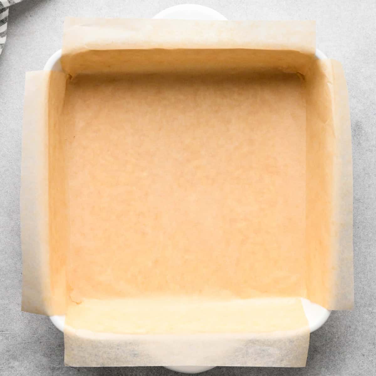 Overhead photo of a white casserole dish lined with parchment paper.