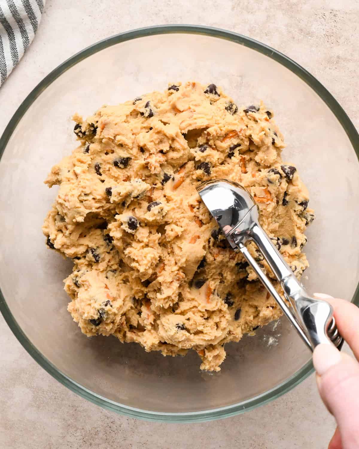 Making kitchen sink cookies - overhead photo of completed cookie dough being scooped out with a cookie scoop.