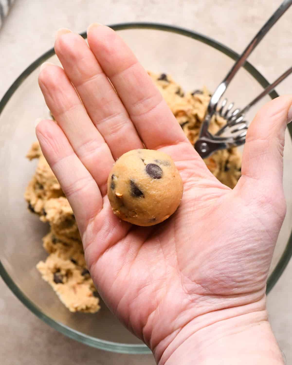 Making kitchen sink cookies - overhead photo of a person's hand holding a rolled-up ball of cookie dough.