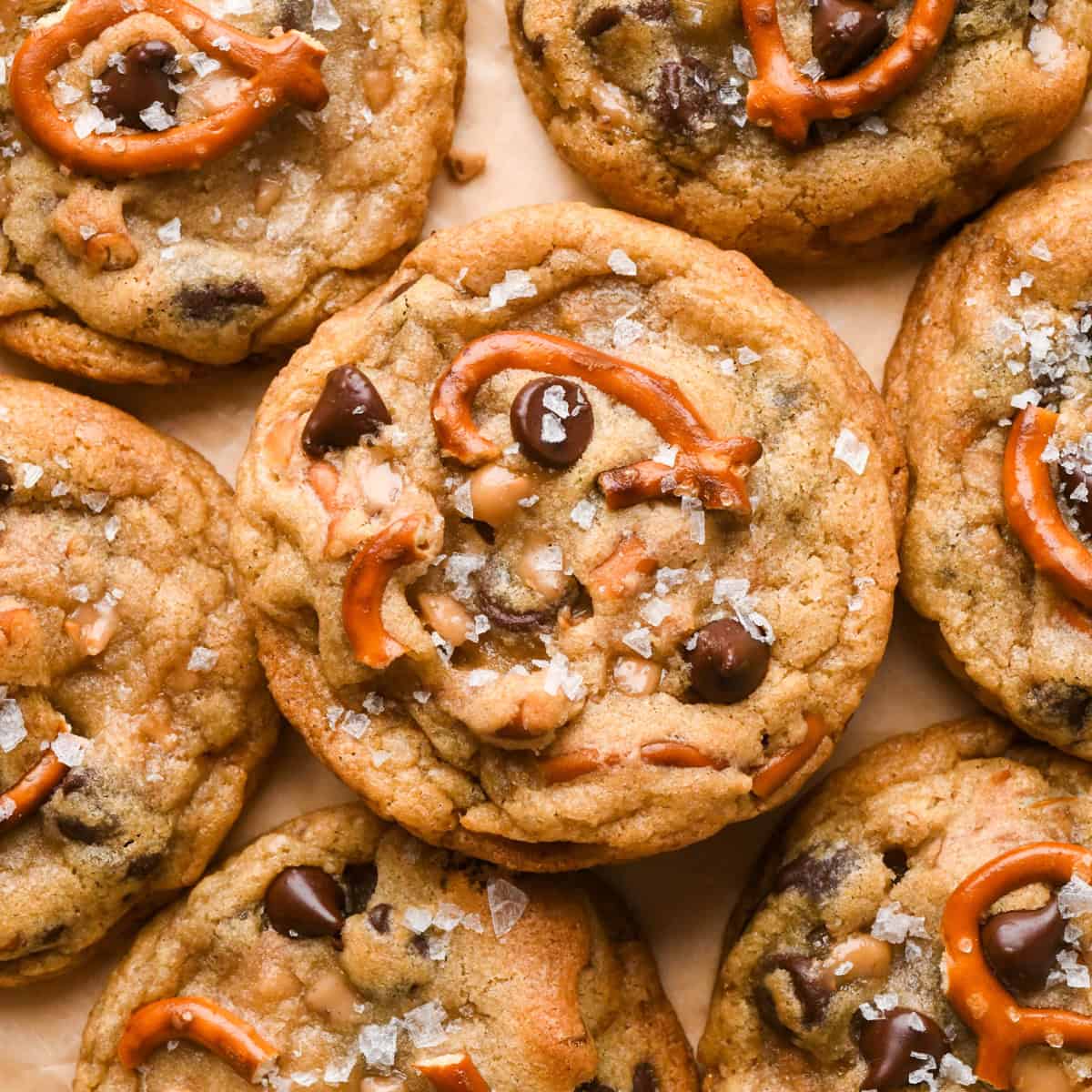 Close-up photo of kitchen sink cookies loaded with chocolate chips, pretzel pieces, and bits of toffee, topped with flaky sea salt.