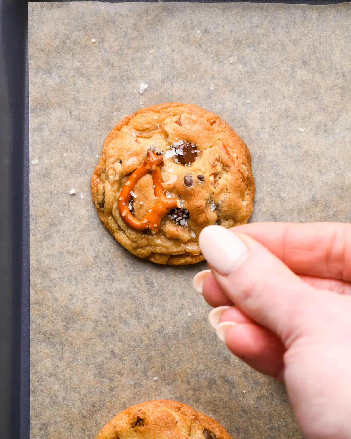 Making kitchen sink cookies - close-up photo of a person holding 1 cookie after it has been baked in the oven.