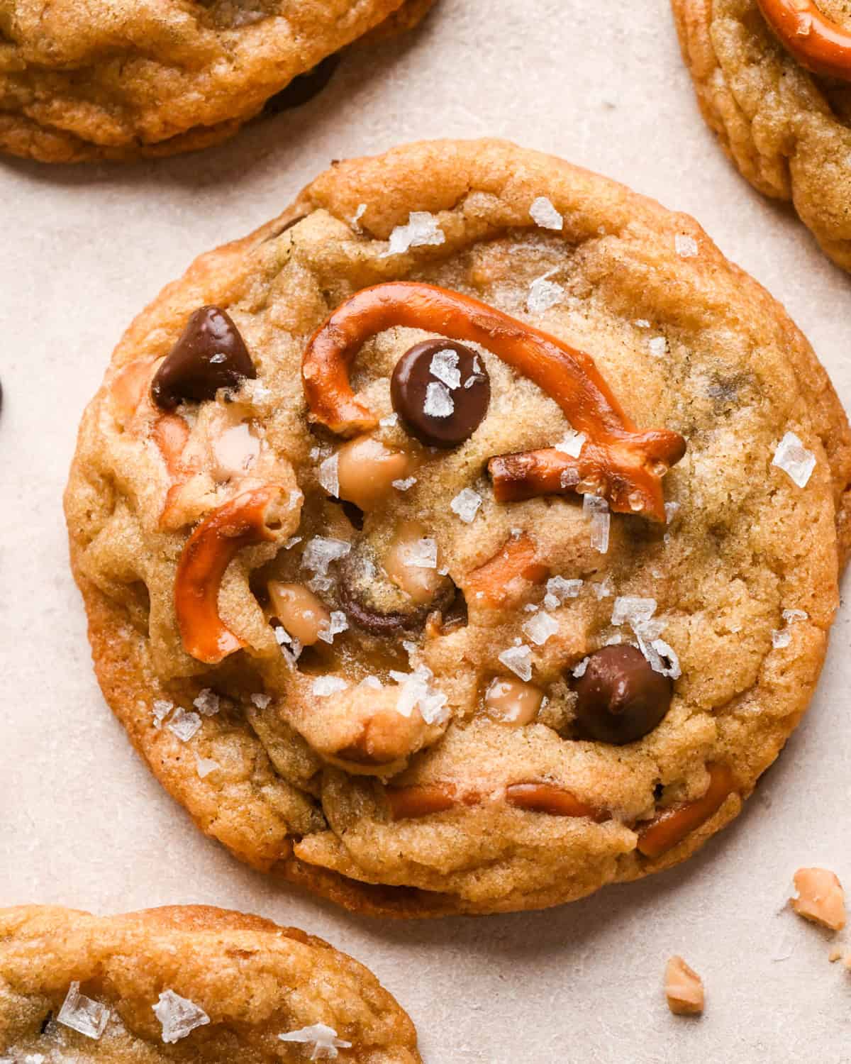 Close-up photo of 1 kitchen sink cookie with chocolate chips, pretzel pieces, toffee pieces, and sea salt visible.