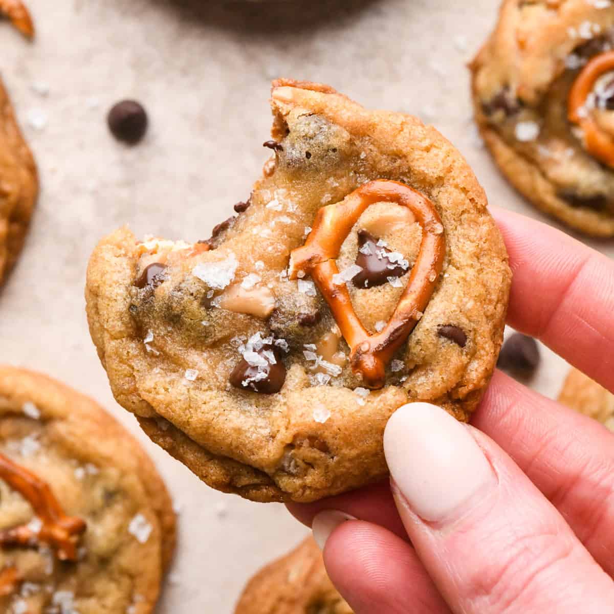Close-up photo of a person holding 1 kitchen sink cookie with a bite taken out of it.