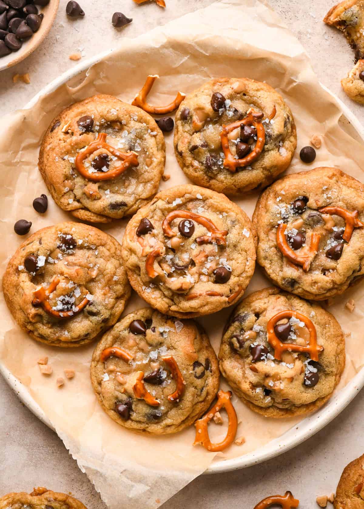 Overhead photo of a batch of kitchen sink cookies being served on a white speckled plate covered with parchment paper.