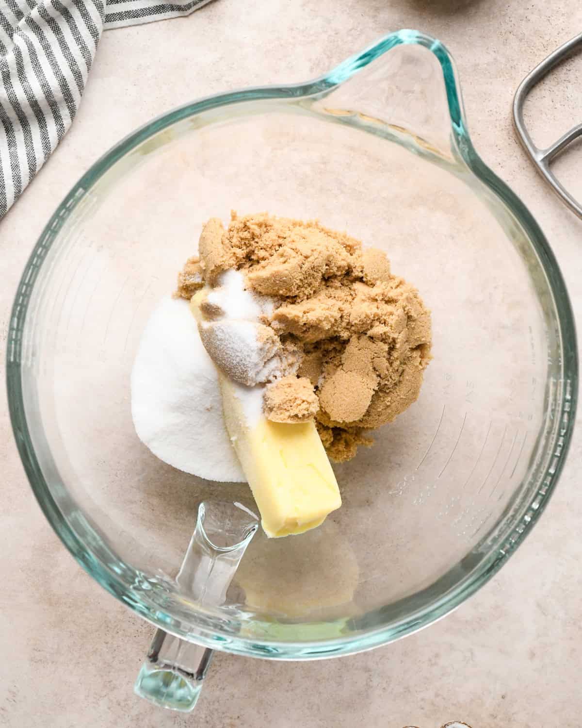 Making kitchen sink cookies - overhead photo of butter, sugar, and brown sugar being added to a clear measuring bowl.
