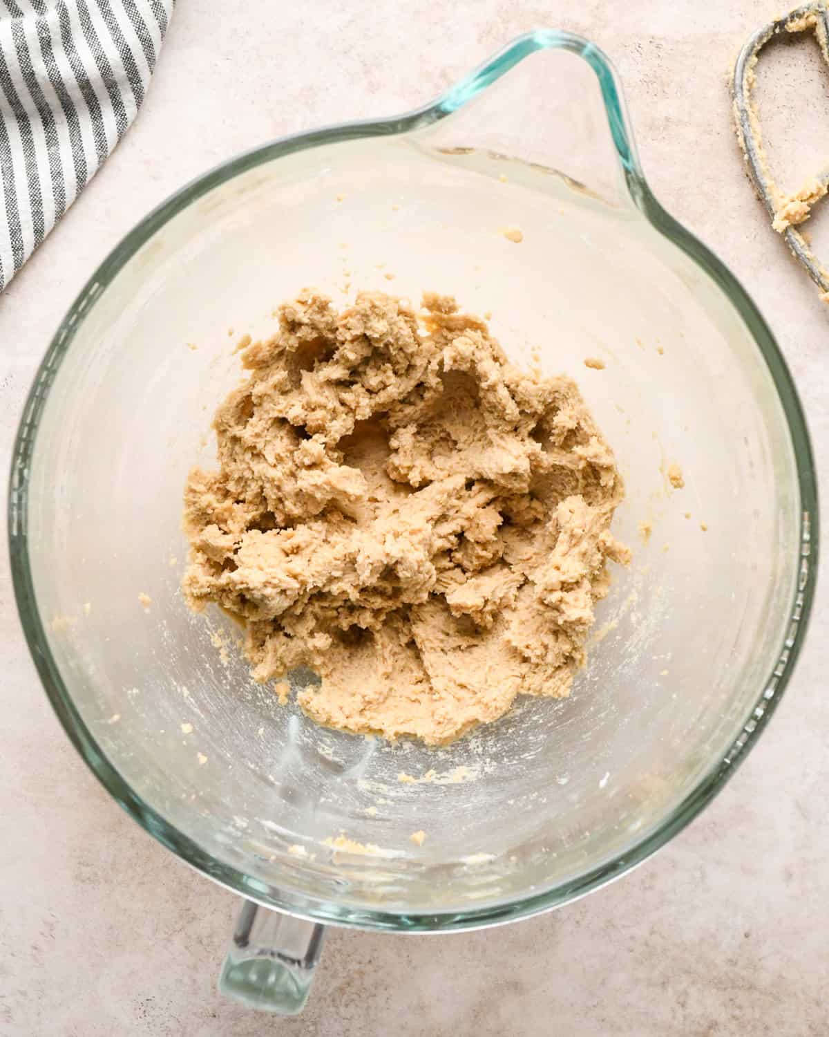 Making kitchen sink cookies - overhead photo of butter, sugar, and brown sugar being added to a clear measuring bowl and mixed together.